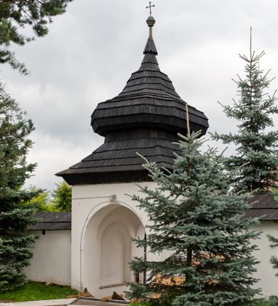 Zdjęcie nr 12: Kościół orientowany, murowany z kamienia, jednonawowy, z prostokątną, trójprzęsłową nawą oraz węższym dwuprzęsłowym prezbiterium zamkniętym trójbocznie, z niewielką prostokątną zakrystią przy północnej ścianie. Od zachodu wieża na planie kwadratu, do północnej ściany nawy dobudowana kaplica Matki Boskiej Karmelitańskiej, do południowej niewielka kruchta. Prezbiterium sklepione żebrowo z jednym rzeźbionym kroksztynem; żebra pokryte późniejszą dekoracją stiukową. Nawa wtórnie sklepiona kolebką z lunetami na gurtach, rozczłonkowana opilastrowanymi półfilarami. Pilastry i zacheuszki ozdobione stiukową ornamentacją. Do zakrystii prowadzi kamienny portal. Kościół opięty grubymi szkarpami jednouskokowymi, nakrytymi daszkami. W dwóch oknach prezbiterium i jednym nawy od południa kamienne maswerki; w zakrystii od wschodu wąskie okienko, tzw. romańskie. W pólnocno-wschodnim narożniku nawy wtórnie wkomponowany rzeźbiony, bardzo zniszczony kroksztyn. Z południowej kruchty do nawy prowadzi kamienny portal o trzech parach kolumienek dźwigających archiwolty. Nawa i prezbiterium nakryte dachem, na ich styku wieżyczka na sygnaturkę. Wieża smukła, bez podziałów architektonicznych, ściany najwyższej kondygnacji cofnięte w głąb, przy krawędzi kamienne kroksztyny, pozostałe po niezachowanej drewnianej hurdycji. Wieża zwieńczona ceglaną attyką, zasłaniającą dwuspadowy dach. W górnej części jej trzonu okna usytuowane z czterech stron. W miejscu hurdycji, na zachodniej ścianie zegar. 

Kościół otoczony niskim murem kamiennym; od zachodu dzwonnica bramna na planie kwadratu z niesklepioną sienią przejściową, nakryta blaszanym hełmem; od południa i od wschodu bramki nakryte hełmami, przy czym jeden pokryty jest gontem, drugi blachą.