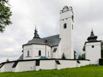 Zdjęcie nr 1: Kościół orientowany, murowany z kamienia, jednonawowy, z prostokątną, trójprzęsłową nawą oraz węższym dwuprzęsłowym prezbiterium zamkniętym trójbocznie, z niewielką prostokątną zakrystią przy północnej ścianie. Od zachodu wieża na planie kwadratu, do północnej ściany nawy dobudowana kaplica Matki Boskiej Karmelitańskiej, do południowej niewielka kruchta. Prezbiterium sklepione żebrowo z jednym rzeźbionym kroksztynem; żebra pokryte późniejszą dekoracją stiukową. Nawa wtórnie sklepiona kolebką z lunetami na gurtach, rozczłonkowana opilastrowanymi półfilarami. Pilastry i zacheuszki ozdobione stiukową ornamentacją. Do zakrystii prowadzi kamienny portal. Kościół opięty grubymi szkarpami jednouskokowymi, nakrytymi daszkami. W dwóch oknach prezbiterium i jednym nawy od południa kamienne maswerki; w zakrystii od wschodu wąskie okienko, tzw. romańskie. W pólnocno-wschodnim narożniku nawy wtórnie wkomponowany rzeźbiony, bardzo zniszczony kroksztyn. Z południowej kruchty do nawy prowadzi kamienny portal o trzech parach kolumienek dźwigających archiwolty. Nawa i prezbiterium nakryte dachem, na ich styku wieżyczka na sygnaturkę. Wieża smukła, bez podziałów architektonicznych, ściany najwyższej kondygnacji cofnięte w głąb, przy krawędzi kamienne kroksztyny, pozostałe po niezachowanej drewnianej hurdycji. Wieża zwieńczona ceglaną attyką, zasłaniającą dwuspadowy dach. W górnej części jej trzonu okna usytuowane z czterech stron. W miejscu hurdycji, na zachodniej ścianie zegar. 

Kościół otoczony niskim murem kamiennym; od zachodu dzwonnica bramna na planie kwadratu z niesklepioną sienią przejściową, nakryta blaszanym hełmem; od południa i od wschodu bramki nakryte hełmami, przy czym jeden pokryty jest gontem, drugi blachą.