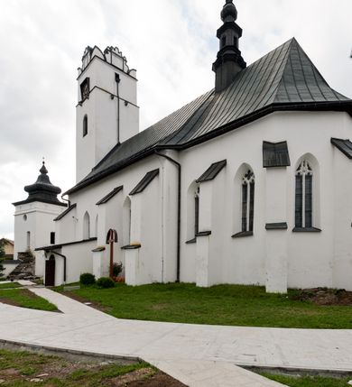 Zdjęcie nr 3: Kościół orientowany, murowany z kamienia, jednonawowy, z prostokątną, trójprzęsłową nawą oraz węższym dwuprzęsłowym prezbiterium zamkniętym trójbocznie, z niewielką prostokątną zakrystią przy północnej ścianie. Od zachodu wieża na planie kwadratu, do północnej ściany nawy dobudowana kaplica Matki Boskiej Karmelitańskiej, do południowej niewielka kruchta. Prezbiterium sklepione żebrowo z jednym rzeźbionym kroksztynem; żebra pokryte późniejszą dekoracją stiukową. Nawa wtórnie sklepiona kolebką z lunetami na gurtach, rozczłonkowana opilastrowanymi półfilarami. Pilastry i zacheuszki ozdobione stiukową ornamentacją. Do zakrystii prowadzi kamienny portal. Kościół opięty grubymi szkarpami jednouskokowymi, nakrytymi daszkami. W dwóch oknach prezbiterium i jednym nawy od południa kamienne maswerki; w zakrystii od wschodu wąskie okienko, tzw. romańskie. W pólnocno-wschodnim narożniku nawy wtórnie wkomponowany rzeźbiony, bardzo zniszczony kroksztyn. Z południowej kruchty do nawy prowadzi kamienny portal o trzech parach kolumienek dźwigających archiwolty. Nawa i prezbiterium nakryte dachem, na ich styku wieżyczka na sygnaturkę. Wieża smukła, bez podziałów architektonicznych, ściany najwyższej kondygnacji cofnięte w głąb, przy krawędzi kamienne kroksztyny, pozostałe po niezachowanej drewnianej hurdycji. Wieża zwieńczona ceglaną attyką, zasłaniającą dwuspadowy dach. W górnej części jej trzonu okna usytuowane z czterech stron. W miejscu hurdycji, na zachodniej ścianie zegar. 

Kościół otoczony niskim murem kamiennym; od zachodu dzwonnica bramna na planie kwadratu z niesklepioną sienią przejściową, nakryta blaszanym hełmem; od południa i od wschodu bramki nakryte hełmami, przy czym jeden pokryty jest gontem, drugi blachą.