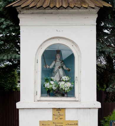 Zdjęcie nr 14: Kościół orientowany, murowany z kamienia, jednonawowy, z prostokątną, trójprzęsłową nawą oraz węższym dwuprzęsłowym prezbiterium zamkniętym trójbocznie, z niewielką prostokątną zakrystią przy północnej ścianie. Od zachodu wieża na planie kwadratu, do północnej ściany nawy dobudowana kaplica Matki Boskiej Karmelitańskiej, do południowej niewielka kruchta. Prezbiterium sklepione żebrowo z jednym rzeźbionym kroksztynem; żebra pokryte późniejszą dekoracją stiukową. Nawa wtórnie sklepiona kolebką z lunetami na gurtach, rozczłonkowana opilastrowanymi półfilarami. Pilastry i zacheuszki ozdobione stiukową ornamentacją. Do zakrystii prowadzi kamienny portal. Kościół opięty grubymi szkarpami jednouskokowymi, nakrytymi daszkami. W dwóch oknach prezbiterium i jednym nawy od południa kamienne maswerki; w zakrystii od wschodu wąskie okienko, tzw. romańskie. W pólnocno-wschodnim narożniku nawy wtórnie wkomponowany rzeźbiony, bardzo zniszczony kroksztyn. Z południowej kruchty do nawy prowadzi kamienny portal o trzech parach kolumienek dźwigających archiwolty. Nawa i prezbiterium nakryte dachem, na ich styku wieżyczka na sygnaturkę. Wieża smukła, bez podziałów architektonicznych, ściany najwyższej kondygnacji cofnięte w głąb, przy krawędzi kamienne kroksztyny, pozostałe po niezachowanej drewnianej hurdycji. Wieża zwieńczona ceglaną attyką, zasłaniającą dwuspadowy dach. W górnej części jej trzonu okna usytuowane z czterech stron. W miejscu hurdycji, na zachodniej ścianie zegar. 

Kościół otoczony niskim murem kamiennym; od zachodu dzwonnica bramna na planie kwadratu z niesklepioną sienią przejściową, nakryta blaszanym hełmem; od południa i od wschodu bramki nakryte hełmami, przy czym jeden pokryty jest gontem, drugi blachą.