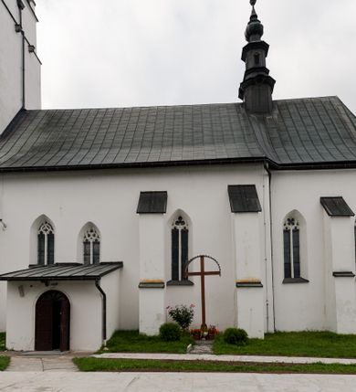 Zdjęcie nr 4: Kościół orientowany, murowany z kamienia, jednonawowy, z prostokątną, trójprzęsłową nawą oraz węższym dwuprzęsłowym prezbiterium zamkniętym trójbocznie, z niewielką prostokątną zakrystią przy północnej ścianie. Od zachodu wieża na planie kwadratu, do północnej ściany nawy dobudowana kaplica Matki Boskiej Karmelitańskiej, do południowej niewielka kruchta. Prezbiterium sklepione żebrowo z jednym rzeźbionym kroksztynem; żebra pokryte późniejszą dekoracją stiukową. Nawa wtórnie sklepiona kolebką z lunetami na gurtach, rozczłonkowana opilastrowanymi półfilarami. Pilastry i zacheuszki ozdobione stiukową ornamentacją. Do zakrystii prowadzi kamienny portal. Kościół opięty grubymi szkarpami jednouskokowymi, nakrytymi daszkami. W dwóch oknach prezbiterium i jednym nawy od południa kamienne maswerki; w zakrystii od wschodu wąskie okienko, tzw. romańskie. W pólnocno-wschodnim narożniku nawy wtórnie wkomponowany rzeźbiony, bardzo zniszczony kroksztyn. Z południowej kruchty do nawy prowadzi kamienny portal o trzech parach kolumienek dźwigających archiwolty. Nawa i prezbiterium nakryte dachem, na ich styku wieżyczka na sygnaturkę. Wieża smukła, bez podziałów architektonicznych, ściany najwyższej kondygnacji cofnięte w głąb, przy krawędzi kamienne kroksztyny, pozostałe po niezachowanej drewnianej hurdycji. Wieża zwieńczona ceglaną attyką, zasłaniającą dwuspadowy dach. W górnej części jej trzonu okna usytuowane z czterech stron. W miejscu hurdycji, na zachodniej ścianie zegar. 

Kościół otoczony niskim murem kamiennym; od zachodu dzwonnica bramna na planie kwadratu z niesklepioną sienią przejściową, nakryta blaszanym hełmem; od południa i od wschodu bramki nakryte hełmami, przy czym jeden pokryty jest gontem, drugi blachą.