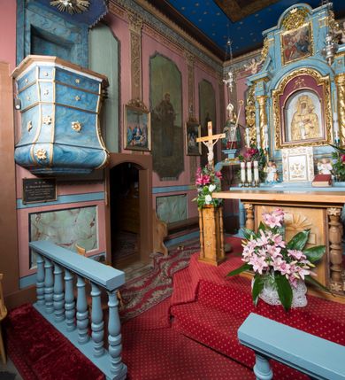 Zdjęcie nr 14: Ołtarz przyścienny, architektoniczny, jednokondygnacyjny ze zwieńczeniem i bramkami. 
Ołtarz prostopadłościenny z mensą wspartą na dwóch tralkach. Antepedium ujęte parą tralek.
Retabulum z uszakami flankowane parą kolumn korynckich o skręcanych trzonach, ustawionych na niskich wysuniętych cokołach. Podpory wspierają odcinki wyłamanego belkowania z architrawem wygiętym w łuk półkolisty. Powyżej belkowania ustawione odcinki wklęsłego przyczółka. 
Zwieńczenie prostopadłościenne z uszakami, zamknięte łukiem nadwieszanym wspieranym przez parę podwójnych pilastrów.
Po bokach ołtarza bramki o wklęsło-wypukłym wykroju z otworami drzwiowymi w kształcie stojącego prostokąta z ćwierćkoliście wklęsłymi górnymi narożami. 
Pole środkowe retabulum w formie wnęki w kształcie prostokąta zamkniętej łukiem nadwieszanym, ujętej podwójnym obramieniem o analogicznym wykroju. We wnęce obraz z przedstawieniem Matki Boskiej z Dzieciątkiem. W antepedium obraz w kształcie leżącego prostokąta z przedstawieniem kielicha z hostią adorowanego przez św. Wojciecha i nieznanego świętego. W zwieńczeniu obraz w kształcie stojącego prostokąta z przedstawieniem Trójcy Świętej ujęty profilowaną ramą.
Nad bramkami, ustawione na cokołach figury św. Wojciecha po prawej oraz św. Stanisława po lewej stronie. Na odcinkach przyczółka ukazane całopostaciowe figury uskrzydlonych aniołków. 
Uszaki ołtarza ażurowe, formowane ze skręconych liści akantu z kwiatami. Wnęka pola środkowego retabulum ujęta szeroką, ażurową ramą formowaną z liści akantu i kwiatów. Poniżej aplikowany monogram maryjny. Po bokach wnęki ornament cekinowy. Poniżej gzymsu ażurowy ornament akantowy. Trzony kolumn oplecione płaskorzeźbioną wicią winorośli. Ścianki cokołów dekorowane płycinami z rzeźbionym liściem akantu. W zwieńczeniu aplikowany rzeźbiony monogram maryjny ujęty wieńcem z koroną. 
Całość struktury ołtarza malowana na jasnobłękitny odcień z marmoryzacją w odcieniach szarości. Profilowania, ornamenty i detal architektoniczny pozłacane.
