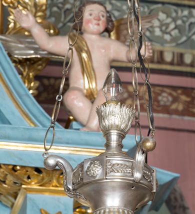 Zdjęcie nr 5: Ołtarz przyścienny, architektoniczny, jednokondygnacyjny ze zwieńczeniem i bramkami. 
Ołtarz prostopadłościenny z mensą wspartą na dwóch tralkach. Antepedium ujęte parą tralek.
Retabulum z uszakami flankowane parą kolumn korynckich o skręcanych trzonach, ustawionych na niskich wysuniętych cokołach. Podpory wspierają odcinki wyłamanego belkowania z architrawem wygiętym w łuk półkolisty. Powyżej belkowania ustawione odcinki wklęsłego przyczółka. 
Zwieńczenie prostopadłościenne z uszakami, zamknięte łukiem nadwieszanym wspieranym przez parę podwójnych pilastrów.
Po bokach ołtarza bramki o wklęsło-wypukłym wykroju z otworami drzwiowymi w kształcie stojącego prostokąta z ćwierćkoliście wklęsłymi górnymi narożami. 
Pole środkowe retabulum w formie wnęki w kształcie prostokąta zamkniętej łukiem nadwieszanym, ujętej podwójnym obramieniem o analogicznym wykroju. We wnęce obraz z przedstawieniem Matki Boskiej z Dzieciątkiem. W antepedium obraz w kształcie leżącego prostokąta z przedstawieniem kielicha z hostią adorowanego przez św. Wojciecha i nieznanego świętego. W zwieńczeniu obraz w kształcie stojącego prostokąta z przedstawieniem Trójcy Świętej ujęty profilowaną ramą.
Nad bramkami, ustawione na cokołach figury św. Wojciecha po prawej oraz św. Stanisława po lewej stronie. Na odcinkach przyczółka ukazane całopostaciowe figury uskrzydlonych aniołków. 
Uszaki ołtarza ażurowe, formowane ze skręconych liści akantu z kwiatami. Wnęka pola środkowego retabulum ujęta szeroką, ażurową ramą formowaną z liści akantu i kwiatów. Poniżej aplikowany monogram maryjny. Po bokach wnęki ornament cekinowy. Poniżej gzymsu ażurowy ornament akantowy. Trzony kolumn oplecione płaskorzeźbioną wicią winorośli. Ścianki cokołów dekorowane płycinami z rzeźbionym liściem akantu. W zwieńczeniu aplikowany rzeźbiony monogram maryjny ujęty wieńcem z koroną. 
Całość struktury ołtarza malowana na jasnobłękitny odcień z marmoryzacją w odcieniach szarości. Profilowania, ornamenty i detal architektoniczny pozłacane.
