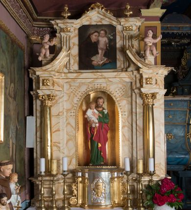 Zdjęcie nr 1: Ołtarz architektoniczny, jednokondygnacyjny, jednoosiowy ze zwieńczeniem. Ołtarz jest prostopadłościenny, z drewnianą mensą. Retabulum osadzone jest na niewysokim, zryzalitowanym cokole. Część środkową nastawy ujmuje para kolumn o korynckich kapitelach, ustawionych na tle zdwojonych pilastrów. Podpory wspierają wyłamujące się ponad nimi belkowanie przerwane w partii architrawu i fryzu. Część środkowa zaaranżowana jest w formie trójbocznej niszy o wykroju zamkniętym łukiem półkolistym, ujętej prostokątną płyciną. Zamknięte trójkątnie zwieńczenie ujęte jest parą pilastrów wspierających gzyms wieńczący. Dodatkowo po bokach znajduje się para niewysokich cokolików oraz przerwany, wklęsły przyczółek. Środkowa płycina antepedium zdobiona jest polichromowanym monogramem maryjnym, ujętym wieńcem kwiatów, płyciny po bokach zdobią wazony z kwiatami. W partii fryzu retabulum oraz na kapitelach pilastrów w zwieńczeniu są motywy rozet. Szczyt zwieńczenia jest w formie ażurowego ornamentu stylizowanej wici roślinnej, po bokach para płomienistych wazonów. W niszy części środkowej retabulum jest figura św. Józefa, w zwieńczeniu obraz w kształcie stojącego prostokąta o ściętych górnych narożach z wizerunkiem św. Antoniego Padewskiego. Na cokolikach ujmujących zwieńczenie usytuowana jest para figur siedzących aniołków.

Struktura ołtarza jest marmoryzowana w odcieniach kremu, beżów i zieleni, detal architektoniczny oraz ornamentyka są złocone.      

