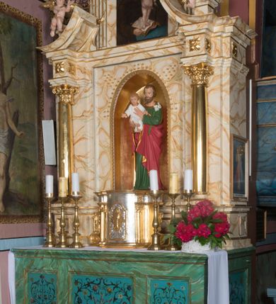Zdjęcie nr 5: Ołtarz architektoniczny, jednokondygnacyjny, jednoosiowy ze zwieńczeniem. Ołtarz jest prostopadłościenny, z drewnianą mensą. Retabulum osadzone jest na niewysokim, zryzalitowanym cokole. Część środkową nastawy ujmuje para kolumn o korynckich kapitelach, ustawionych na tle zdwojonych pilastrów. Podpory wspierają wyłamujące się ponad nimi belkowanie przerwane w partii architrawu i fryzu. Część środkowa zaaranżowana jest w formie trójbocznej niszy o wykroju zamkniętym łukiem półkolistym, ujętej prostokątną płyciną. Zamknięte trójkątnie zwieńczenie ujęte jest parą pilastrów wspierających gzyms wieńczący. Dodatkowo po bokach znajduje się para niewysokich cokolików oraz przerwany, wklęsły przyczółek. Środkowa płycina antepedium zdobiona jest polichromowanym monogramem maryjnym, ujętym wieńcem kwiatów, płyciny po bokach zdobią wazony z kwiatami. W partii fryzu retabulum oraz na kapitelach pilastrów w zwieńczeniu są motywy rozet. Szczyt zwieńczenia jest w formie ażurowego ornamentu stylizowanej wici roślinnej, po bokach para płomienistych wazonów. W niszy części środkowej retabulum jest figura św. Józefa, w zwieńczeniu obraz w kształcie stojącego prostokąta o ściętych górnych narożach z wizerunkiem św. Antoniego Padewskiego. Na cokolikach ujmujących zwieńczenie usytuowana jest para figur siedzących aniołków.

Struktura ołtarza jest marmoryzowana w odcieniach kremu, beżów i zieleni, detal architektoniczny oraz ornamentyka są złocone.      
