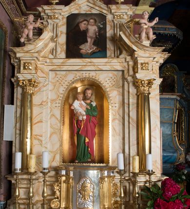 Zdjęcie nr 2: Ołtarz architektoniczny, jednokondygnacyjny, jednoosiowy ze zwieńczeniem. Ołtarz jest prostopadłościenny, z drewnianą mensą. Retabulum osadzone jest na niewysokim, zryzalitowanym cokole. Część środkową nastawy ujmuje para kolumn o korynckich kapitelach, ustawionych na tle zdwojonych pilastrów. Podpory wspierają wyłamujące się ponad nimi belkowanie przerwane w partii architrawu i fryzu. Część środkowa zaaranżowana jest w formie trójbocznej niszy o wykroju zamkniętym łukiem półkolistym, ujętej prostokątną płyciną. Zamknięte trójkątnie zwieńczenie ujęte jest parą pilastrów wspierających gzyms wieńczący. Dodatkowo po bokach znajduje się para niewysokich cokolików oraz przerwany, wklęsły przyczółek. Środkowa płycina antepedium zdobiona jest polichromowanym monogramem maryjnym, ujętym wieńcem kwiatów, płyciny po bokach zdobią wazony z kwiatami. W partii fryzu retabulum oraz na kapitelach pilastrów w zwieńczeniu są motywy rozet. Szczyt zwieńczenia jest w formie ażurowego ornamentu stylizowanej wici roślinnej, po bokach para płomienistych wazonów. W niszy części środkowej retabulum jest figura św. Józefa, w zwieńczeniu obraz w kształcie stojącego prostokąta o ściętych górnych narożach z wizerunkiem św. Antoniego Padewskiego. Na cokolikach ujmujących zwieńczenie usytuowana jest para figur siedzących aniołków.

Struktura ołtarza jest marmoryzowana w odcieniach kremu, beżów i zieleni, detal architektoniczny oraz ornamentyka są złocone.      
