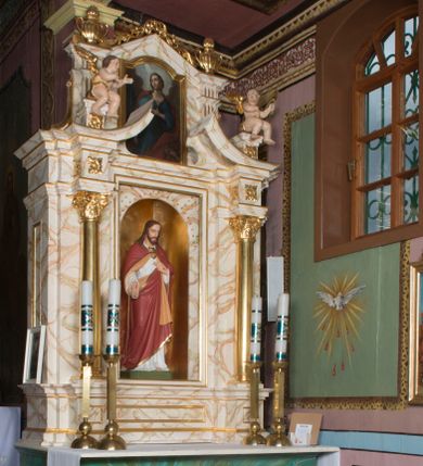 Zdjęcie nr 1: Ołtarz architektoniczny, jednokondygnacyjny, jednoosiowy ze zwieńczeniem. Ołtarz jest prostopadłościenny, z drewnianą mensą. Retabulum osadzone jest na niewysokim, zryzalitowanym cokole. Część środkową nastawy ujmuje para kolumn o korynckich kapitelach, ustawionych na tle zdwojonych pilastrów. Podpory wspierają wyłamujące się ponad nimi belkowanie przerwane w partii architrawu i fryzu. Część środkowa zaaranżowana jest w formie trójbocznej niszy o wykroju zamkniętym łukiem półkolistym, ujętej prostokątną płyciną. Zamknięte trójkątnie zwieńczenie ujęte jest parą pilastrów wspierających gzyms wieńczący. Dodatkowo po bokach znajduje się para niewysokich cokolików oraz przerwany, wklęsły przyczółek o fantazyjnym wykroju. Środkowa płycina antepedium zdobiona jest polichromowanym monogramem chrystologicznym, płyciny po bokach różanymi krzewami. W partii fryzu retabulum oraz na cokolikach w zwieńczeniu są motywy rozet. Szczyt zwieńczenia jest w formie ażurowego ornamentu stylizowanej wici roślinnej, po bokach para płomienistych wazonów. W niszy części środkowej retabulum jest figura Najświętszego Serca Jezusa, w zwieńczeniu obraz w kształcie stojącego prostokąta zamkniętego nadwieszonym łukiem odcinkowym, ujęty profilowaną, złoconą ramą, zawiera wizerunek św. Małgorzaty. Na cokolikach ujmujących zwieńczenie usytuowana jest para figur siedzących aniołków.

Struktura ołtarza jest marmoryzowana w odcieniach kremu, beżów i zieleni, detal architektoniczny oraz ornamentyka są złocone.      
