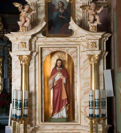 Zdjęcie nr 2: Ołtarz architektoniczny, jednokondygnacyjny, jednoosiowy ze zwieńczeniem. Ołtarz jest prostopadłościenny, z drewnianą mensą. Retabulum osadzone jest na niewysokim, zryzalitowanym cokole. Część środkową nastawy ujmuje para kolumn o korynckich kapitelach, ustawionych na tle zdwojonych pilastrów. Podpory wspierają wyłamujące się ponad nimi belkowanie przerwane w partii architrawu i fryzu. Część środkowa zaaranżowana jest w formie trójbocznej niszy o wykroju zamkniętym łukiem półkolistym, ujętej prostokątną płyciną. Zamknięte trójkątnie zwieńczenie ujęte jest parą pilastrów wspierających gzyms wieńczący. Dodatkowo po bokach znajduje się para niewysokich cokolików oraz przerwany, wklęsły przyczółek o fantazyjnym wykroju. Środkowa płycina antepedium zdobiona jest polichromowanym monogramem chrystologicznym, płyciny po bokach różanymi krzewami. W partii fryzu retabulum oraz na cokolikach w zwieńczeniu są motywy rozet. Szczyt zwieńczenia jest w formie ażurowego ornamentu stylizowanej wici roślinnej, po bokach para płomienistych wazonów. W niszy części środkowej retabulum jest figura Najświętszego Serca Jezusa, w zwieńczeniu obraz w kształcie stojącego prostokąta zamkniętego nadwieszonym łukiem odcinkowym, ujęty profilowaną, złoconą ramą, zawiera wizerunek św. Małgorzaty. Na cokolikach ujmujących zwieńczenie usytuowana jest para figur siedzących aniołków.

Struktura ołtarza jest marmoryzowana w odcieniach kremu, beżów i zieleni, detal architektoniczny oraz ornamentyka są złocone.      
