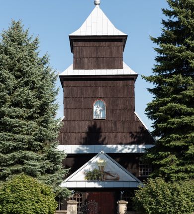 Zdjęcie nr 59: Kościół drewniany o konstrukcji zrębowej, elewacje jednolite, szalowane gontem. Wieża i kruchta zachodnia o konstrukcji słupowo-ramowej, narożne słupy nośne wzmocnione krzyżami św. Andrzeja. Więźba dachowa drewniana, krokwiowa. Budynek na kamiennym podmurowaniu. 
Kościół orientowany, jednonawowy, nawa na rzucie prostokąta zbliżonego do kwadratu, prezbiterium nieco węższe, wydłużone, zakończone trójbocznie. Do północnej ściany prezbiterium przylega zakrystia na planie prostokąta. Przy zachodniej ścianie nawy wieża na planie zbliżonym do prostokąta, o lekko ukośnej ścianie południowej. Od zachodu do wieży przylega kruchta na rzucie prostokąta. 
W przyziemiu wieży babiniec połączony z nawą wtórnym otworem w ścianie. Pomiędzy nawą a prezbiterium otwór tęczowy. Parapet chóru muzycznego w zachodniej części nawy, wsparty na czterech drewnianych kolumnach, z wejściem z nawy po drabiniastych schodach. Ściany i sklepienia pokryte polichromią z iluzjonistyczną architekturą i scenami figuralnymi. Wnętrze nakryte pułapami deskowymi w nawie i prezbiterium oraz stropem belkowym w babińcu. Otwory drzwiowe o prostokątnym wykroju zamknięte drzwiami obitymi deskami w kruchcie zachodniej, w ścianie południowej nawy oraz z prezbiterium do zakrystii. Okna w formie stojącego prostokąta. Posadzka kamienna, z płyt marmurowych. 
Elewacja frontowa jednoosiowa. Na osi wejście do kruchty zachodniej. Korpus wieży podzielony poziomo daszkami okapowymi, na froncie okno. Elewacje boczne jednolite. Korpus nawowy przepruty oknami po dwa na ścianach północnej i południowej, prezbiterium z oknem na ścianie południowej oraz dwoma okienkami na ścianach zamknięcia. Na elewacji wschodniej zawieszony krucyfiks. 
Kościół nakryty dachami dwuspadowymi, o pokryciu blaszanym, wyższym nad nawą, niższym nad prezbiterium. W połowie długości dachu, nad nawą, wbudowana wieżyczka na sygnaturkę, na ośmiobocznym, obitym blachą trzonie, z latarnią zwieńczoną niewielkim hełmem. Wieża nakryta czterospadowym daszkiem namiotowym, zwieńczona kulistą puszką i krzyżem. Kruchta nakryta osobnym daszkiem dwuspadowym, półszczytowym, zakrystia niższym dachem pulpitowym.
