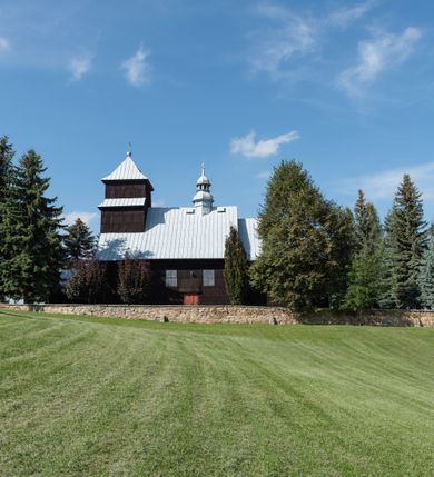 Zdjęcie nr 2: Kościół drewniany o konstrukcji zrębowej, elewacje jednolite, szalowane gontem. Wieża i kruchta zachodnia o konstrukcji słupowo-ramowej, narożne słupy nośne wzmocnione krzyżami św. Andrzeja. Więźba dachowa drewniana, krokwiowa. Budynek na kamiennym podmurowaniu. 
Kościół orientowany, jednonawowy, nawa na rzucie prostokąta zbliżonego do kwadratu, prezbiterium nieco węższe, wydłużone, zakończone trójbocznie. Do północnej ściany prezbiterium przylega zakrystia na planie prostokąta. Przy zachodniej ścianie nawy wieża na planie zbliżonym do prostokąta, o lekko ukośnej ścianie południowej. Od zachodu do wieży przylega kruchta na rzucie prostokąta. 
W przyziemiu wieży babiniec połączony z nawą wtórnym otworem w ścianie. Pomiędzy nawą a prezbiterium otwór tęczowy. Parapet chóru muzycznego w zachodniej części nawy, wsparty na czterech drewnianych kolumnach, z wejściem z nawy po drabiniastych schodach. Ściany i sklepienia pokryte polichromią z iluzjonistyczną architekturą i scenami figuralnymi. Wnętrze nakryte pułapami deskowymi w nawie i prezbiterium oraz stropem belkowym w babińcu. Otwory drzwiowe o prostokątnym wykroju zamknięte drzwiami obitymi deskami w kruchcie zachodniej, w ścianie południowej nawy oraz z prezbiterium do zakrystii. Okna w formie stojącego prostokąta. Posadzka kamienna, z płyt marmurowych. 
Elewacja frontowa jednoosiowa. Na osi wejście do kruchty zachodniej. Korpus wieży podzielony poziomo daszkami okapowymi, na froncie okno. Elewacje boczne jednolite. Korpus nawowy przepruty oknami po dwa na ścianach północnej i południowej, prezbiterium z oknem na ścianie południowej oraz dwoma okienkami na ścianach zamknięcia. Na elewacji wschodniej zawieszony krucyfiks. 
Kościół nakryty dachami dwuspadowymi, o pokryciu blaszanym, wyższym nad nawą, niższym nad prezbiterium. W połowie długości dachu, nad nawą, wbudowana wieżyczka na sygnaturkę, na ośmiobocznym, obitym blachą trzonie, z latarnią zwieńczoną niewielkim hełmem. Wieża nakryta czterospadowym daszkiem namiotowym, zwieńczona kulistą puszką i krzyżem. Kruchta nakryta osobnym daszkiem dwuspadowym, półszczytowym, zakrystia niższym dachem pulpitowym.
