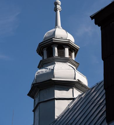 Zdjęcie nr 30: Kościół drewniany o konstrukcji zrębowej, elewacje jednolite, szalowane gontem. Wieża i kruchta zachodnia o konstrukcji słupowo-ramowej, narożne słupy nośne wzmocnione krzyżami św. Andrzeja. Więźba dachowa drewniana, krokwiowa. Budynek na kamiennym podmurowaniu. 
Kościół orientowany, jednonawowy, nawa na rzucie prostokąta zbliżonego do kwadratu, prezbiterium nieco węższe, wydłużone, zakończone trójbocznie. Do północnej ściany prezbiterium przylega zakrystia na planie prostokąta. Przy zachodniej ścianie nawy wieża na planie zbliżonym do prostokąta, o lekko ukośnej ścianie południowej. Od zachodu do wieży przylega kruchta na rzucie prostokąta. 
W przyziemiu wieży babiniec połączony z nawą wtórnym otworem w ścianie. Pomiędzy nawą a prezbiterium otwór tęczowy. Parapet chóru muzycznego w zachodniej części nawy, wsparty na czterech drewnianych kolumnach, z wejściem z nawy po drabiniastych schodach. Ściany i sklepienia pokryte polichromią z iluzjonistyczną architekturą i scenami figuralnymi. Wnętrze nakryte pułapami deskowymi w nawie i prezbiterium oraz stropem belkowym w babińcu. Otwory drzwiowe o prostokątnym wykroju zamknięte drzwiami obitymi deskami w kruchcie zachodniej, w ścianie południowej nawy oraz z prezbiterium do zakrystii. Okna w formie stojącego prostokąta. Posadzka kamienna, z płyt marmurowych. 
Elewacja frontowa jednoosiowa. Na osi wejście do kruchty zachodniej. Korpus wieży podzielony poziomo daszkami okapowymi, na froncie okno. Elewacje boczne jednolite. Korpus nawowy przepruty oknami po dwa na ścianach północnej i południowej, prezbiterium z oknem na ścianie południowej oraz dwoma okienkami na ścianach zamknięcia. Na elewacji wschodniej zawieszony krucyfiks. 
Kościół nakryty dachami dwuspadowymi, o pokryciu blaszanym, wyższym nad nawą, niższym nad prezbiterium. W połowie długości dachu, nad nawą, wbudowana wieżyczka na sygnaturkę, na ośmiobocznym, obitym blachą trzonie, z latarnią zwieńczoną niewielkim hełmem. Wieża nakryta czterospadowym daszkiem namiotowym, zwieńczona kulistą puszką i krzyżem. Kruchta nakryta osobnym daszkiem dwuspadowym, półszczytowym, zakrystia niższym dachem pulpitowym.
