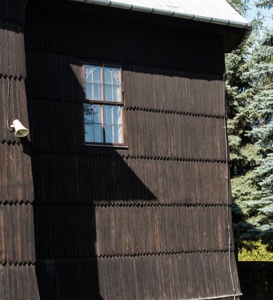 Zdjęcie nr 14: Kościół drewniany o konstrukcji zrębowej, elewacje jednolite, szalowane gontem. Wieża i kruchta zachodnia o konstrukcji słupowo-ramowej, narożne słupy nośne wzmocnione krzyżami św. Andrzeja. Więźba dachowa drewniana, krokwiowa. Budynek na kamiennym podmurowaniu. 
Kościół orientowany, jednonawowy, nawa na rzucie prostokąta zbliżonego do kwadratu, prezbiterium nieco węższe, wydłużone, zakończone trójbocznie. Do północnej ściany prezbiterium przylega zakrystia na planie prostokąta. Przy zachodniej ścianie nawy wieża na planie zbliżonym do prostokąta, o lekko ukośnej ścianie południowej. Od zachodu do wieży przylega kruchta na rzucie prostokąta. 
W przyziemiu wieży babiniec połączony z nawą wtórnym otworem w ścianie. Pomiędzy nawą a prezbiterium otwór tęczowy. Parapet chóru muzycznego w zachodniej części nawy, wsparty na czterech drewnianych kolumnach, z wejściem z nawy po drabiniastych schodach. Ściany i sklepienia pokryte polichromią z iluzjonistyczną architekturą i scenami figuralnymi. Wnętrze nakryte pułapami deskowymi w nawie i prezbiterium oraz stropem belkowym w babińcu. Otwory drzwiowe o prostokątnym wykroju zamknięte drzwiami obitymi deskami w kruchcie zachodniej, w ścianie południowej nawy oraz z prezbiterium do zakrystii. Okna w formie stojącego prostokąta. Posadzka kamienna, z płyt marmurowych. 
Elewacja frontowa jednoosiowa. Na osi wejście do kruchty zachodniej. Korpus wieży podzielony poziomo daszkami okapowymi, na froncie okno. Elewacje boczne jednolite. Korpus nawowy przepruty oknami po dwa na ścianach północnej i południowej, prezbiterium z oknem na ścianie południowej oraz dwoma okienkami na ścianach zamknięcia. Na elewacji wschodniej zawieszony krucyfiks. 
Kościół nakryty dachami dwuspadowymi, o pokryciu blaszanym, wyższym nad nawą, niższym nad prezbiterium. W połowie długości dachu, nad nawą, wbudowana wieżyczka na sygnaturkę, na ośmiobocznym, obitym blachą trzonie, z latarnią zwieńczoną niewielkim hełmem. Wieża nakryta czterospadowym daszkiem namiotowym, zwieńczona kulistą puszką i krzyżem. Kruchta nakryta osobnym daszkiem dwuspadowym, półszczytowym, zakrystia niższym dachem pulpitowym.
