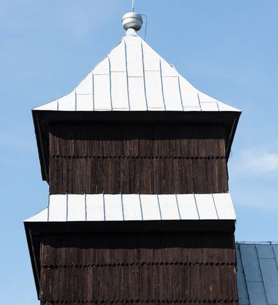 Zdjęcie nr 25: Kościół drewniany o konstrukcji zrębowej, elewacje jednolite, szalowane gontem. Wieża i kruchta zachodnia o konstrukcji słupowo-ramowej, narożne słupy nośne wzmocnione krzyżami św. Andrzeja. Więźba dachowa drewniana, krokwiowa. Budynek na kamiennym podmurowaniu. 
Kościół orientowany, jednonawowy, nawa na rzucie prostokąta zbliżonego do kwadratu, prezbiterium nieco węższe, wydłużone, zakończone trójbocznie. Do północnej ściany prezbiterium przylega zakrystia na planie prostokąta. Przy zachodniej ścianie nawy wieża na planie zbliżonym do prostokąta, o lekko ukośnej ścianie południowej. Od zachodu do wieży przylega kruchta na rzucie prostokąta. 
W przyziemiu wieży babiniec połączony z nawą wtórnym otworem w ścianie. Pomiędzy nawą a prezbiterium otwór tęczowy. Parapet chóru muzycznego w zachodniej części nawy, wsparty na czterech drewnianych kolumnach, z wejściem z nawy po drabiniastych schodach. Ściany i sklepienia pokryte polichromią z iluzjonistyczną architekturą i scenami figuralnymi. Wnętrze nakryte pułapami deskowymi w nawie i prezbiterium oraz stropem belkowym w babińcu. Otwory drzwiowe o prostokątnym wykroju zamknięte drzwiami obitymi deskami w kruchcie zachodniej, w ścianie południowej nawy oraz z prezbiterium do zakrystii. Okna w formie stojącego prostokąta. Posadzka kamienna, z płyt marmurowych. 
Elewacja frontowa jednoosiowa. Na osi wejście do kruchty zachodniej. Korpus wieży podzielony poziomo daszkami okapowymi, na froncie okno. Elewacje boczne jednolite. Korpus nawowy przepruty oknami po dwa na ścianach północnej i południowej, prezbiterium z oknem na ścianie południowej oraz dwoma okienkami na ścianach zamknięcia. Na elewacji wschodniej zawieszony krucyfiks. 
Kościół nakryty dachami dwuspadowymi, o pokryciu blaszanym, wyższym nad nawą, niższym nad prezbiterium. W połowie długości dachu, nad nawą, wbudowana wieżyczka na sygnaturkę, na ośmiobocznym, obitym blachą trzonie, z latarnią zwieńczoną niewielkim hełmem. Wieża nakryta czterospadowym daszkiem namiotowym, zwieńczona kulistą puszką i krzyżem. Kruchta nakryta osobnym daszkiem dwuspadowym, półszczytowym, zakrystia niższym dachem pulpitowym.
