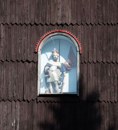 Zdjęcie nr 43: Kościół drewniany o konstrukcji zrębowej, elewacje jednolite, szalowane gontem. Wieża i kruchta zachodnia o konstrukcji słupowo-ramowej, narożne słupy nośne wzmocnione krzyżami św. Andrzeja. Więźba dachowa drewniana, krokwiowa. Budynek na kamiennym podmurowaniu. 
Kościół orientowany, jednonawowy, nawa na rzucie prostokąta zbliżonego do kwadratu, prezbiterium nieco węższe, wydłużone, zakończone trójbocznie. Do północnej ściany prezbiterium przylega zakrystia na planie prostokąta. Przy zachodniej ścianie nawy wieża na planie zbliżonym do prostokąta, o lekko ukośnej ścianie południowej. Od zachodu do wieży przylega kruchta na rzucie prostokąta. 
W przyziemiu wieży babiniec połączony z nawą wtórnym otworem w ścianie. Pomiędzy nawą a prezbiterium otwór tęczowy. Parapet chóru muzycznego w zachodniej części nawy, wsparty na czterech drewnianych kolumnach, z wejściem z nawy po drabiniastych schodach. Ściany i sklepienia pokryte polichromią z iluzjonistyczną architekturą i scenami figuralnymi. Wnętrze nakryte pułapami deskowymi w nawie i prezbiterium oraz stropem belkowym w babińcu. Otwory drzwiowe o prostokątnym wykroju zamknięte drzwiami obitymi deskami w kruchcie zachodniej, w ścianie południowej nawy oraz z prezbiterium do zakrystii. Okna w formie stojącego prostokąta. Posadzka kamienna, z płyt marmurowych. 
Elewacja frontowa jednoosiowa. Na osi wejście do kruchty zachodniej. Korpus wieży podzielony poziomo daszkami okapowymi, na froncie okno. Elewacje boczne jednolite. Korpus nawowy przepruty oknami po dwa na ścianach północnej i południowej, prezbiterium z oknem na ścianie południowej oraz dwoma okienkami na ścianach zamknięcia. Na elewacji wschodniej zawieszony krucyfiks. 
Kościół nakryty dachami dwuspadowymi, o pokryciu blaszanym, wyższym nad nawą, niższym nad prezbiterium. W połowie długości dachu, nad nawą, wbudowana wieżyczka na sygnaturkę, na ośmiobocznym, obitym blachą trzonie, z latarnią zwieńczoną niewielkim hełmem. Wieża nakryta czterospadowym daszkiem namiotowym, zwieńczona kulistą puszką i krzyżem. Kruchta nakryta osobnym daszkiem dwuspadowym, półszczytowym, zakrystia niższym dachem pulpitowym.
