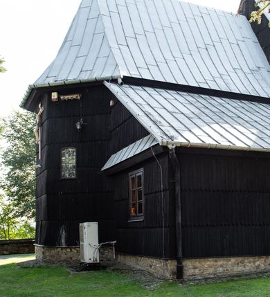 Zdjęcie nr 20: Kościół drewniany o konstrukcji zrębowej, elewacje jednolite, szalowane gontem. Wieża i kruchta zachodnia o konstrukcji słupowo-ramowej, narożne słupy nośne wzmocnione krzyżami św. Andrzeja. Więźba dachowa drewniana, krokwiowa. Budynek na kamiennym podmurowaniu. 
Kościół orientowany, jednonawowy, nawa na rzucie prostokąta zbliżonego do kwadratu, prezbiterium nieco węższe, wydłużone, zakończone trójbocznie. Do północnej ściany prezbiterium przylega zakrystia na planie prostokąta. Przy zachodniej ścianie nawy wieża na planie zbliżonym do prostokąta, o lekko ukośnej ścianie południowej. Od zachodu do wieży przylega kruchta na rzucie prostokąta. 
W przyziemiu wieży babiniec połączony z nawą wtórnym otworem w ścianie. Pomiędzy nawą a prezbiterium otwór tęczowy. Parapet chóru muzycznego w zachodniej części nawy, wsparty na czterech drewnianych kolumnach, z wejściem z nawy po drabiniastych schodach. Ściany i sklepienia pokryte polichromią z iluzjonistyczną architekturą i scenami figuralnymi. Wnętrze nakryte pułapami deskowymi w nawie i prezbiterium oraz stropem belkowym w babińcu. Otwory drzwiowe o prostokątnym wykroju zamknięte drzwiami obitymi deskami w kruchcie zachodniej, w ścianie południowej nawy oraz z prezbiterium do zakrystii. Okna w formie stojącego prostokąta. Posadzka kamienna, z płyt marmurowych. 
Elewacja frontowa jednoosiowa. Na osi wejście do kruchty zachodniej. Korpus wieży podzielony poziomo daszkami okapowymi, na froncie okno. Elewacje boczne jednolite. Korpus nawowy przepruty oknami po dwa na ścianach północnej i południowej, prezbiterium z oknem na ścianie południowej oraz dwoma okienkami na ścianach zamknięcia. Na elewacji wschodniej zawieszony krucyfiks. 
Kościół nakryty dachami dwuspadowymi, o pokryciu blaszanym, wyższym nad nawą, niższym nad prezbiterium. W połowie długości dachu, nad nawą, wbudowana wieżyczka na sygnaturkę, na ośmiobocznym, obitym blachą trzonie, z latarnią zwieńczoną niewielkim hełmem. Wieża nakryta czterospadowym daszkiem namiotowym, zwieńczona kulistą puszką i krzyżem. Kruchta nakryta osobnym daszkiem dwuspadowym, półszczytowym, zakrystia niższym dachem pulpitowym.
