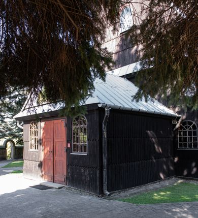 Zdjęcie nr 4: Kościół drewniany o konstrukcji zrębowej, elewacje jednolite, szalowane gontem. Wieża i kruchta zachodnia o konstrukcji słupowo-ramowej, narożne słupy nośne wzmocnione krzyżami św. Andrzeja. Więźba dachowa drewniana, krokwiowa. Budynek na kamiennym podmurowaniu. 
Kościół orientowany, jednonawowy, nawa na rzucie prostokąta zbliżonego do kwadratu, prezbiterium nieco węższe, wydłużone, zakończone trójbocznie. Do północnej ściany prezbiterium przylega zakrystia na planie prostokąta. Przy zachodniej ścianie nawy wieża na planie zbliżonym do prostokąta, o lekko ukośnej ścianie południowej. Od zachodu do wieży przylega kruchta na rzucie prostokąta. 
W przyziemiu wieży babiniec połączony z nawą wtórnym otworem w ścianie. Pomiędzy nawą a prezbiterium otwór tęczowy. Parapet chóru muzycznego w zachodniej części nawy, wsparty na czterech drewnianych kolumnach, z wejściem z nawy po drabiniastych schodach. Ściany i sklepienia pokryte polichromią z iluzjonistyczną architekturą i scenami figuralnymi. Wnętrze nakryte pułapami deskowymi w nawie i prezbiterium oraz stropem belkowym w babińcu. Otwory drzwiowe o prostokątnym wykroju zamknięte drzwiami obitymi deskami w kruchcie zachodniej, w ścianie południowej nawy oraz z prezbiterium do zakrystii. Okna w formie stojącego prostokąta. Posadzka kamienna, z płyt marmurowych. 
Elewacja frontowa jednoosiowa. Na osi wejście do kruchty zachodniej. Korpus wieży podzielony poziomo daszkami okapowymi, na froncie okno. Elewacje boczne jednolite. Korpus nawowy przepruty oknami po dwa na ścianach północnej i południowej, prezbiterium z oknem na ścianie południowej oraz dwoma okienkami na ścianach zamknięcia. Na elewacji wschodniej zawieszony krucyfiks. 
Kościół nakryty dachami dwuspadowymi, o pokryciu blaszanym, wyższym nad nawą, niższym nad prezbiterium. W połowie długości dachu, nad nawą, wbudowana wieżyczka na sygnaturkę, na ośmiobocznym, obitym blachą trzonie, z latarnią zwieńczoną niewielkim hełmem. Wieża nakryta czterospadowym daszkiem namiotowym, zwieńczona kulistą puszką i krzyżem. Kruchta nakryta osobnym daszkiem dwuspadowym, półszczytowym, zakrystia niższym dachem pulpitowym.
