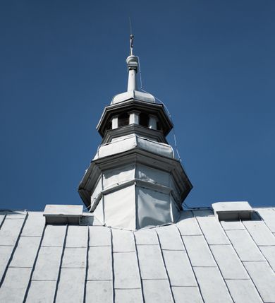 Zdjęcie nr 28: Kościół drewniany o konstrukcji zrębowej, elewacje jednolite, szalowane gontem. Wieża i kruchta zachodnia o konstrukcji słupowo-ramowej, narożne słupy nośne wzmocnione krzyżami św. Andrzeja. Więźba dachowa drewniana, krokwiowa. Budynek na kamiennym podmurowaniu. 
Kościół orientowany, jednonawowy, nawa na rzucie prostokąta zbliżonego do kwadratu, prezbiterium nieco węższe, wydłużone, zakończone trójbocznie. Do północnej ściany prezbiterium przylega zakrystia na planie prostokąta. Przy zachodniej ścianie nawy wieża na planie zbliżonym do prostokąta, o lekko ukośnej ścianie południowej. Od zachodu do wieży przylega kruchta na rzucie prostokąta. 
W przyziemiu wieży babiniec połączony z nawą wtórnym otworem w ścianie. Pomiędzy nawą a prezbiterium otwór tęczowy. Parapet chóru muzycznego w zachodniej części nawy, wsparty na czterech drewnianych kolumnach, z wejściem z nawy po drabiniastych schodach. Ściany i sklepienia pokryte polichromią z iluzjonistyczną architekturą i scenami figuralnymi. Wnętrze nakryte pułapami deskowymi w nawie i prezbiterium oraz stropem belkowym w babińcu. Otwory drzwiowe o prostokątnym wykroju zamknięte drzwiami obitymi deskami w kruchcie zachodniej, w ścianie południowej nawy oraz z prezbiterium do zakrystii. Okna w formie stojącego prostokąta. Posadzka kamienna, z płyt marmurowych. 
Elewacja frontowa jednoosiowa. Na osi wejście do kruchty zachodniej. Korpus wieży podzielony poziomo daszkami okapowymi, na froncie okno. Elewacje boczne jednolite. Korpus nawowy przepruty oknami po dwa na ścianach północnej i południowej, prezbiterium z oknem na ścianie południowej oraz dwoma okienkami na ścianach zamknięcia. Na elewacji wschodniej zawieszony krucyfiks. 
Kościół nakryty dachami dwuspadowymi, o pokryciu blaszanym, wyższym nad nawą, niższym nad prezbiterium. W połowie długości dachu, nad nawą, wbudowana wieżyczka na sygnaturkę, na ośmiobocznym, obitym blachą trzonie, z latarnią zwieńczoną niewielkim hełmem. Wieża nakryta czterospadowym daszkiem namiotowym, zwieńczona kulistą puszką i krzyżem. Kruchta nakryta osobnym daszkiem dwuspadowym, półszczytowym, zakrystia niższym dachem pulpitowym.
