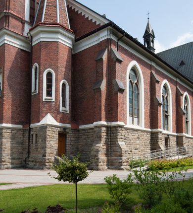 Zdjęcie nr 4: Kościół orientowany, składający się trójnawowej, czteroprzęsłowej pseudohali z transeptem oraz z jednoprzęsłowym, zamkniętym trójbocznie prezbiterium, przy którym od północy usytuowana jest zakrystia, a od południa skarbiec, zamknięte dwubocznie. Od fasady, na przedłużeniu nawy, usytuowana jest czteroboczna wieża, a przy niej ośmioboczne wieżyczki schodowe. Kościół ustawiony jest na wysokim, kamiennym cokole. Wieża trójkondygnacyjna: w dolnej kondygnacji ostrołukowy portal w obramieniu z kolumienkami i wimpergą, nad nim rozeta; w drugiej, ostrołukowe okno z maswerkiem; w trzeciej tryforium. Ściany wieży są zwieńczone szczytami, a wieżyczki schodowe ostrosłupowymi ceglanymi hełmami. Elewacje opięte są przyporami, zwieńczone gzymsem. Okna ostrołukowe z maswerkami, w tynkowanych na biało obramieniach. Dachy dwuspadowe, nad zakrystią i skarbcem pulpitowe, hełm wieży ostrosłupowy; pokrycie blachą. Empora organowa znajduje się w zachodnim przęśle nawy. Sklepienia krzyżowo-żebrowe, przy prezbiterium – gwiaździste. Nawy oddzielone kolumnami o kapitelach pączkowych; na ścianach naw bocznych pilastry. Chór muzyczny na kolumnach z kapitelami kostkowymi. Okna prostokątne zakończone ostrołukowo, w prezbiterium: jednodzielne, usytuowane w trzech ścianach zamknięcia chóru, z witrażami; w korpusie nawowym: trój- i dwudzielne, w pierwszych (wschodnich) trzech przęsłach z witrażami. Żebra sklepienne podkreślone polichromią. Portal główny zdobi tondo z płaskorzeźbą Najświętszego Serca Pana Jezusa.