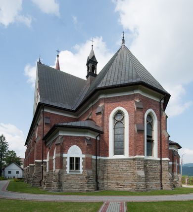 Zdjęcie nr 13: Kościół orientowany, składający się trójnawowej, czteroprzęsłowej pseudohali z transeptem oraz z jednoprzęsłowym, zamkniętym trójbocznie prezbiterium, przy którym od północy usytuowana jest zakrystia, a od południa skarbiec, zamknięte dwubocznie. Od fasady, na przedłużeniu nawy, usytuowana jest czteroboczna wieża, a przy niej ośmioboczne wieżyczki schodowe. Kościół ustawiony jest na wysokim, kamiennym cokole. Wieża trójkondygnacyjna: w dolnej kondygnacji ostrołukowy portal w obramieniu z kolumienkami i wimpergą, nad nim rozeta; w drugiej, ostrołukowe okno z maswerkiem; w trzeciej tryforium. Ściany wieży są zwieńczone szczytami, a wieżyczki schodowe ostrosłupowymi ceglanymi hełmami. Elewacje opięte są przyporami, zwieńczone gzymsem. Okna ostrołukowe z maswerkami, w tynkowanych na biało obramieniach. Dachy dwuspadowe, nad zakrystią i skarbcem pulpitowe, hełm wieży ostrosłupowy; pokrycie blachą. Empora organowa znajduje się w zachodnim przęśle nawy. Sklepienia krzyżowo-żebrowe, przy prezbiterium – gwiaździste. Nawy oddzielone kolumnami o kapitelach pączkowych; na ścianach naw bocznych pilastry. Chór muzyczny na kolumnach z kapitelami kostkowymi. Okna prostokątne zakończone ostrołukowo, w prezbiterium: jednodzielne, usytuowane w trzech ścianach zamknięcia chóru, z witrażami; w korpusie nawowym: trój- i dwudzielne, w pierwszych (wschodnich) trzech przęsłach z witrażami. Żebra sklepienne podkreślone polichromią. Portal główny zdobi tondo z płaskorzeźbą Najświętszego Serca Pana Jezusa.