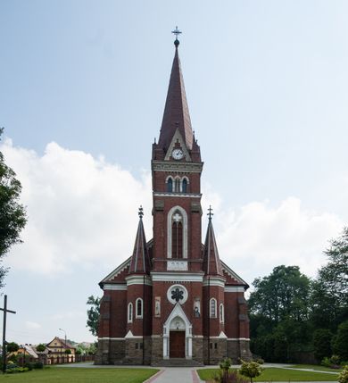 Zdjęcie nr 5: Kościół orientowany, składający się trójnawowej, czteroprzęsłowej pseudohali z transeptem oraz z jednoprzęsłowym, zamkniętym trójbocznie prezbiterium, przy którym od północy usytuowana jest zakrystia, a od południa skarbiec, zamknięte dwubocznie. Od fasady, na przedłużeniu nawy, usytuowana jest czteroboczna wieża, a przy niej ośmioboczne wieżyczki schodowe. Kościół ustawiony jest na wysokim, kamiennym cokole. Wieża trójkondygnacyjna: w dolnej kondygnacji ostrołukowy portal w obramieniu z kolumienkami i wimpergą, nad nim rozeta; w drugiej, ostrołukowe okno z maswerkiem; w trzeciej tryforium. Ściany wieży są zwieńczone szczytami, a wieżyczki schodowe ostrosłupowymi ceglanymi hełmami. Elewacje opięte są przyporami, zwieńczone gzymsem. Okna ostrołukowe z maswerkami, w tynkowanych na biało obramieniach. Dachy dwuspadowe, nad zakrystią i skarbcem pulpitowe, hełm wieży ostrosłupowy; pokrycie blachą. Empora organowa znajduje się w zachodnim przęśle nawy. Sklepienia krzyżowo-żebrowe, przy prezbiterium – gwiaździste. Nawy oddzielone kolumnami o kapitelach pączkowych; na ścianach naw bocznych pilastry. Chór muzyczny na kolumnach z kapitelami kostkowymi. Okna prostokątne zakończone ostrołukowo, w prezbiterium: jednodzielne, usytuowane w trzech ścianach zamknięcia chóru, z witrażami; w korpusie nawowym: trój- i dwudzielne, w pierwszych (wschodnich) trzech przęsłach z witrażami. Żebra sklepienne podkreślone polichromią. Portal główny zdobi tondo z płaskorzeźbą Najświętszego Serca Pana Jezusa.