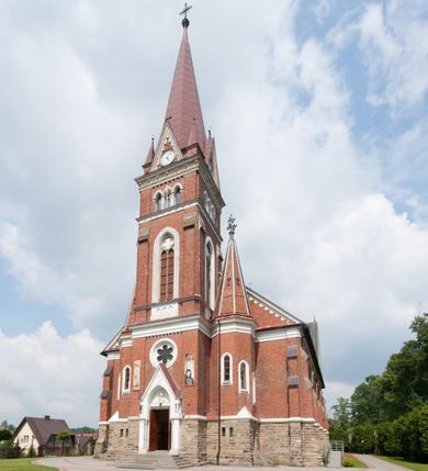 Zdjęcie nr 9: Kościół orientowany, składający się trójnawowej, czteroprzęsłowej pseudohali z transeptem oraz z jednoprzęsłowym, zamkniętym trójbocznie prezbiterium, przy którym od północy usytuowana jest zakrystia, a od południa skarbiec, zamknięte dwubocznie. Od fasady, na przedłużeniu nawy, usytuowana jest czteroboczna wieża, a przy niej ośmioboczne wieżyczki schodowe. Kościół ustawiony jest na wysokim, kamiennym cokole. Wieża trójkondygnacyjna: w dolnej kondygnacji ostrołukowy portal w obramieniu z kolumienkami i wimpergą, nad nim rozeta; w drugiej, ostrołukowe okno z maswerkiem; w trzeciej tryforium. Ściany wieży są zwieńczone szczytami, a wieżyczki schodowe ostrosłupowymi ceglanymi hełmami. Elewacje opięte są przyporami, zwieńczone gzymsem. Okna ostrołukowe z maswerkami, w tynkowanych na biało obramieniach. Dachy dwuspadowe, nad zakrystią i skarbcem pulpitowe, hełm wieży ostrosłupowy; pokrycie blachą. Empora organowa znajduje się w zachodnim przęśle nawy. Sklepienia krzyżowo-żebrowe, przy prezbiterium – gwiaździste. Nawy oddzielone kolumnami o kapitelach pączkowych; na ścianach naw bocznych pilastry. Chór muzyczny na kolumnach z kapitelami kostkowymi. Okna prostokątne zakończone ostrołukowo, w prezbiterium: jednodzielne, usytuowane w trzech ścianach zamknięcia chóru, z witrażami; w korpusie nawowym: trój- i dwudzielne, w pierwszych (wschodnich) trzech przęsłach z witrażami. Żebra sklepienne podkreślone polichromią. Portal główny zdobi tondo z płaskorzeźbą Najświętszego Serca Pana Jezusa.
