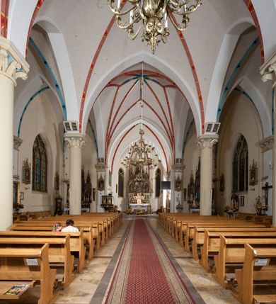 Zdjęcie nr 16: Kościół orientowany, składający się trójnawowej, czteroprzęsłowej pseudohali z transeptem oraz z jednoprzęsłowym, zamkniętym trójbocznie prezbiterium, przy którym od północy usytuowana jest zakrystia, a od południa skarbiec, zamknięte dwubocznie. Od fasady, na przedłużeniu nawy, usytuowana jest czteroboczna wieża, a przy niej ośmioboczne wieżyczki schodowe. Kościół ustawiony jest na wysokim, kamiennym cokole. Wieża trójkondygnacyjna: w dolnej kondygnacji ostrołukowy portal w obramieniu z kolumienkami i wimpergą, nad nim rozeta; w drugiej, ostrołukowe okno z maswerkiem; w trzeciej tryforium. Ściany wieży są zwieńczone szczytami, a wieżyczki schodowe ostrosłupowymi ceglanymi hełmami. Elewacje opięte są przyporami, zwieńczone gzymsem. Okna ostrołukowe z maswerkami, w tynkowanych na biało obramieniach. Dachy dwuspadowe, nad zakrystią i skarbcem pulpitowe, hełm wieży ostrosłupowy; pokrycie blachą. Empora organowa znajduje się w zachodnim przęśle nawy. Sklepienia krzyżowo-żebrowe, przy prezbiterium – gwiaździste. Nawy oddzielone kolumnami o kapitelach pączkowych; na ścianach naw bocznych pilastry. Chór muzyczny na kolumnach z kapitelami kostkowymi. Okna prostokątne zakończone ostrołukowo, w prezbiterium: jednodzielne, usytuowane w trzech ścianach zamknięcia chóru, z witrażami; w korpusie nawowym: trój- i dwudzielne, w pierwszych (wschodnich) trzech przęsłach z witrażami. Żebra sklepienne podkreślone polichromią. Portal główny zdobi tondo z płaskorzeźbą Najświętszego Serca Pana Jezusa.
