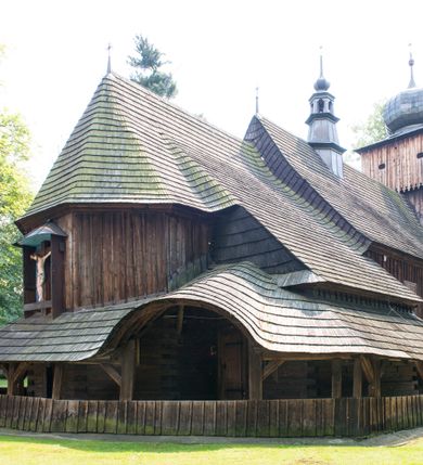 Zdjęcie nr 19: Kościół orientowany, drewniany, na podmurowaniu, o konstrukcji zrębowej, z wieżą o konstrukcji słupowo-ramowej. Składa się z prostokątnej nawy, do której od wschodu przylega węższe prezbiterium zamknięte trójbocznie. Do niego od północy dobudowano prostokątną zakrystię. Do nawy od zachodu przylega wieża na rzucie kwadratu, o ścianach pochyłych, rozdzielona na kondygnacje daszkiem; zwieńczona nadwieszoną izbicą szalowaną pionowymi deskami wyciętymi dołem w ozdobną koronkę; w ścianach izbicy po dwa małe okienka. 
Kościół jednonawowy, z węższym prezbiterium oddzielonym ścianą tęczową. Otwór tęczowy podwójny, górny mniejszy, w strefie sklepień, dolny większy, wycięty w zrębie. Na podniebiu dolnego łuku napis „TEN KOŚCIÓŁ ZAŁOŻONY RP 1789 BENEDYKOWANY RP 1792 MALOWANY RP 1930”. Ściany gładkie, pokryte dekoracją malarską imitującą detale architektoniczne: kolumny, belkowanie, obramienia okien, plafony wypełnione rzeźbiarską dekoracją; między nimi postacie świętych. W nawie od zachodu chór muzyczny wsparty na dwóch, profilowanych słupach, z parapetem wybrzuszonym pośrodku. Nawa i prezbiterium nakryte pozornym sklepieniem kolebkowym z płaskimi odcinkami stropowymi po bokach. 
W nawie głównej cztery okna, w prezbiterium dwa, wszystkie w kształcie stojącego prostokąta; w dolnej kondygnacji wieży dwa okna w kształcie leżącego prostokąta. Wejście główne od zachodu, kolejne od południa, oba portale zamknięte od góry łukiem „w ośli grzbiet”; portal z prezbiterium do zakrystii.  
Kościół obiegają soboty, czyli rodzaj podcieni, zamkniętych wokół wieży, otwartych na pozostałej długości; z kruchtami od zachodu i od południa; cztery kwadratowe okienka w sobotach od zachodu. 
Ściany na zewnątrz kościoła pobite deskami. Nad nawą główną dach dwuspadowy, nad prezbiterium wielopołaciowy, przedłużony od północy na zakrystię. Na dachu nawy zwężająca się ku górze wieżyczka na sygnaturkę, która przechodzi w latarnię o cebulastym zakończeniu. Wieżę zachodnią wieńczy hełm złożony z niskiego dachu namiotowego i nasadzonej na niego bani z kulą i krzyżem. Soboty nakryto dachem pulpitowym, wygiętym przy ścianie wschodniej zakrystii łukowo ku górze po to, aby lepiej ją doświetlić. Dachy kryte gontami, hełmy wież blachą. 
