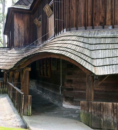 Zdjęcie nr 22: Kościół orientowany, drewniany, na podmurowaniu, o konstrukcji zrębowej, z wieżą o konstrukcji słupowo-ramowej. Składa się z prostokątnej nawy, do której od wschodu przylega węższe prezbiterium zamknięte trójbocznie. Do niego od północy dobudowano prostokątną zakrystię. Do nawy od zachodu przylega wieża na rzucie kwadratu, o ścianach pochyłych, rozdzielona na kondygnacje daszkiem; zwieńczona nadwieszoną izbicą szalowaną pionowymi deskami wyciętymi dołem w ozdobną koronkę; w ścianach izbicy po dwa małe okienka. 
Kościół jednonawowy, z węższym prezbiterium oddzielonym ścianą tęczową. Otwór tęczowy podwójny, górny mniejszy, w strefie sklepień, dolny większy, wycięty w zrębie. Na podniebiu dolnego łuku napis „TEN KOŚCIÓŁ ZAŁOŻONY RP 1789 BENEDYKOWANY RP 1792 MALOWANY RP 1930”. Ściany gładkie, pokryte dekoracją malarską imitującą detale architektoniczne: kolumny, belkowanie, obramienia okien, plafony wypełnione rzeźbiarską dekoracją; między nimi postacie świętych. W nawie od zachodu chór muzyczny wsparty na dwóch, profilowanych słupach, z parapetem wybrzuszonym pośrodku. Nawa i prezbiterium nakryte pozornym sklepieniem kolebkowym z płaskimi odcinkami stropowymi po bokach. 
W nawie głównej cztery okna, w prezbiterium dwa, wszystkie w kształcie stojącego prostokąta; w dolnej kondygnacji wieży dwa okna w kształcie leżącego prostokąta. Wejście główne od zachodu, kolejne od południa, oba portale zamknięte od góry łukiem „w ośli grzbiet”; portal z prezbiterium do zakrystii.  
Kościół obiegają soboty, czyli rodzaj podcieni, zamkniętych wokół wieży, otwartych na pozostałej długości; z kruchtami od zachodu i od południa; cztery kwadratowe okienka w sobotach od zachodu. 
Ściany na zewnątrz kościoła pobite deskami. Nad nawą główną dach dwuspadowy, nad prezbiterium wielopołaciowy, przedłużony od północy na zakrystię. Na dachu nawy zwężająca się ku górze wieżyczka na sygnaturkę, która przechodzi w latarnię o cebulastym zakończeniu. Wieżę zachodnią wieńczy hełm złożony z niskiego dachu namiotowego i nasadzonej na niego bani z kulą i krzyżem. Soboty nakryto dachem pulpitowym, wygiętym przy ścianie wschodniej zakrystii łukowo ku górze po to, aby lepiej ją doświetlić. Dachy kryte gontami, hełmy wież blachą. 
