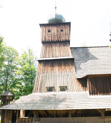 Zdjęcie nr 11: Kościół orientowany, drewniany, na podmurowaniu, o konstrukcji zrębowej, z wieżą o konstrukcji słupowo-ramowej. Składa się z prostokątnej nawy, do której od wschodu przylega węższe prezbiterium zamknięte trójbocznie. Do niego od północy dobudowano prostokątną zakrystię. Do nawy od zachodu przylega wieża na rzucie kwadratu, o ścianach pochyłych, rozdzielona na kondygnacje daszkiem; zwieńczona nadwieszoną izbicą szalowaną pionowymi deskami wyciętymi dołem w ozdobną koronkę; w ścianach izbicy po dwa małe okienka. 
Kościół jednonawowy, z węższym prezbiterium oddzielonym ścianą tęczową. Otwór tęczowy podwójny, górny mniejszy, w strefie sklepień, dolny większy, wycięty w zrębie. Na podniebiu dolnego łuku napis „TEN KOŚCIÓŁ ZAŁOŻONY RP 1789 BENEDYKOWANY RP 1792 MALOWANY RP 1930”. Ściany gładkie, pokryte dekoracją malarską imitującą detale architektoniczne: kolumny, belkowanie, obramienia okien, plafony wypełnione rzeźbiarską dekoracją; między nimi postacie świętych. W nawie od zachodu chór muzyczny wsparty na dwóch, profilowanych słupach, z parapetem wybrzuszonym pośrodku. Nawa i prezbiterium nakryte pozornym sklepieniem kolebkowym z płaskimi odcinkami stropowymi po bokach. 
W nawie głównej cztery okna, w prezbiterium dwa, wszystkie w kształcie stojącego prostokąta; w dolnej kondygnacji wieży dwa okna w kształcie leżącego prostokąta. Wejście główne od zachodu, kolejne od południa, oba portale zamknięte od góry łukiem „w ośli grzbiet”; portal z prezbiterium do zakrystii.  
Kościół obiegają soboty, czyli rodzaj podcieni, zamkniętych wokół wieży, otwartych na pozostałej długości; z kruchtami od zachodu i od południa; cztery kwadratowe okienka w sobotach od zachodu. 
Ściany na zewnątrz kościoła pobite deskami. Nad nawą główną dach dwuspadowy, nad prezbiterium wielopołaciowy, przedłużony od północy na zakrystię. Na dachu nawy zwężająca się ku górze wieżyczka na sygnaturkę, która przechodzi w latarnię o cebulastym zakończeniu. Wieżę zachodnią wieńczy hełm złożony z niskiego dachu namiotowego i nasadzonej na niego bani z kulą i krzyżem. Soboty nakryto dachem pulpitowym, wygiętym przy ścianie wschodniej zakrystii łukowo ku górze po to, aby lepiej ją doświetlić. Dachy kryte gontami, hełmy wież blachą. 
