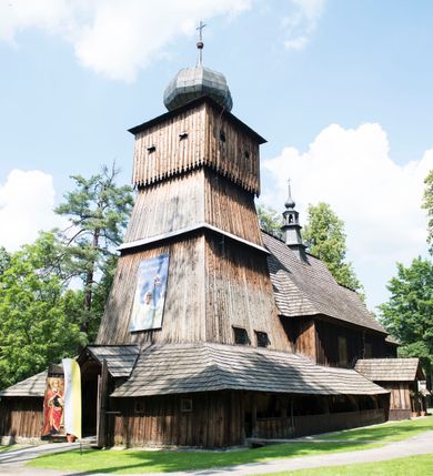 Zdjęcie nr 67: Kościół orientowany, drewniany, na podmurowaniu, o konstrukcji zrębowej, z wieżą o konstrukcji słupowo-ramowej. Składa się z prostokątnej nawy, do której od wschodu przylega węższe prezbiterium zamknięte trójbocznie. Do niego od północy dobudowano prostokątną zakrystię. Do nawy od zachodu przylega wieża na rzucie kwadratu, o ścianach pochyłych, rozdzielona na kondygnacje daszkiem; zwieńczona nadwieszoną izbicą szalowaną pionowymi deskami wyciętymi dołem w ozdobną koronkę; w ścianach izbicy po dwa małe okienka. 
Kościół jednonawowy, z węższym prezbiterium oddzielonym ścianą tęczową. Otwór tęczowy podwójny, górny mniejszy, w strefie sklepień, dolny większy, wycięty w zrębie. Na podniebiu dolnego łuku napis „TEN KOŚCIÓŁ ZAŁOŻONY RP 1789 BENEDYKOWANY RP 1792 MALOWANY RP 1930”. Ściany gładkie, pokryte dekoracją malarską imitującą detale architektoniczne: kolumny, belkowanie, obramienia okien, plafony wypełnione rzeźbiarską dekoracją; między nimi postacie świętych. W nawie od zachodu chór muzyczny wsparty na dwóch, profilowanych słupach, z parapetem wybrzuszonym pośrodku. Nawa i prezbiterium nakryte pozornym sklepieniem kolebkowym z płaskimi odcinkami stropowymi po bokach. 
W nawie głównej cztery okna, w prezbiterium dwa, wszystkie w kształcie stojącego prostokąta; w dolnej kondygnacji wieży dwa okna w kształcie leżącego prostokąta. Wejście główne od zachodu, kolejne od południa, oba portale zamknięte od góry łukiem „w ośli grzbiet”; portal z prezbiterium do zakrystii.  
Kościół obiegają soboty, czyli rodzaj podcieni, zamkniętych wokół wieży, otwartych na pozostałej długości; z kruchtami od zachodu i od południa; cztery kwadratowe okienka w sobotach od zachodu. 
Ściany na zewnątrz kościoła pobite deskami. Nad nawą główną dach dwuspadowy, nad prezbiterium wielopołaciowy, przedłużony od północy na zakrystię. Na dachu nawy zwężająca się ku górze wieżyczka na sygnaturkę, która przechodzi w latarnię o cebulastym zakończeniu. Wieżę zachodnią wieńczy hełm złożony z niskiego dachu namiotowego i nasadzonej na niego bani z kulą i krzyżem. Soboty nakryto dachem pulpitowym, wygiętym przy ścianie wschodniej zakrystii łukowo ku górze po to, aby lepiej ją doświetlić. Dachy kryte gontami, hełmy wież blachą. 
