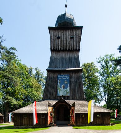 Zdjęcie nr 4: Kościół orientowany, drewniany, na podmurowaniu, o konstrukcji zrębowej, z wieżą o konstrukcji słupowo-ramowej. Składa się z prostokątnej nawy, do której od wschodu przylega węższe prezbiterium zamknięte trójbocznie. Do niego od północy dobudowano prostokątną zakrystię. Do nawy od zachodu przylega wieża na rzucie kwadratu, o ścianach pochyłych, rozdzielona na kondygnacje daszkiem; zwieńczona nadwieszoną izbicą szalowaną pionowymi deskami wyciętymi dołem w ozdobną koronkę; w ścianach izbicy po dwa małe okienka. 
Kościół jednonawowy, z węższym prezbiterium oddzielonym ścianą tęczową. Otwór tęczowy podwójny, górny mniejszy, w strefie sklepień, dolny większy, wycięty w zrębie. Na podniebiu dolnego łuku napis „TEN KOŚCIÓŁ ZAŁOŻONY RP 1789 BENEDYKOWANY RP 1792 MALOWANY RP 1930”. Ściany gładkie, pokryte dekoracją malarską imitującą detale architektoniczne: kolumny, belkowanie, obramienia okien, plafony wypełnione rzeźbiarską dekoracją; między nimi postacie świętych. W nawie od zachodu chór muzyczny wsparty na dwóch, profilowanych słupach, z parapetem wybrzuszonym pośrodku. Nawa i prezbiterium nakryte pozornym sklepieniem kolebkowym z płaskimi odcinkami stropowymi po bokach. 
W nawie głównej cztery okna, w prezbiterium dwa, wszystkie w kształcie stojącego prostokąta; w dolnej kondygnacji wieży dwa okna w kształcie leżącego prostokąta. Wejście główne od zachodu, kolejne od południa, oba portale zamknięte od góry łukiem „w ośli grzbiet”; portal z prezbiterium do zakrystii.  
Kościół obiegają soboty, czyli rodzaj podcieni, zamkniętych wokół wieży, otwartych na pozostałej długości; z kruchtami od zachodu i od południa; cztery kwadratowe okienka w sobotach od zachodu. 
Ściany na zewnątrz kościoła pobite deskami. Nad nawą główną dach dwuspadowy, nad prezbiterium wielopołaciowy, przedłużony od północy na zakrystię. Na dachu nawy zwężająca się ku górze wieżyczka na sygnaturkę, która przechodzi w latarnię o cebulastym zakończeniu. Wieżę zachodnią wieńczy hełm złożony z niskiego dachu namiotowego i nasadzonej na niego bani z kulą i krzyżem. Soboty nakryto dachem pulpitowym, wygiętym przy ścianie wschodniej zakrystii łukowo ku górze po to, aby lepiej ją doświetlić. Dachy kryte gontami, hełmy wież blachą. 
