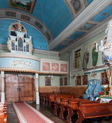 Zdjęcie nr 59: Kościół orientowany, drewniany, na podmurowaniu, o konstrukcji zrębowej, z wieżą o konstrukcji słupowo-ramowej. Składa się z prostokątnej nawy, do której od wschodu przylega węższe prezbiterium zamknięte trójbocznie. Do niego od północy dobudowano prostokątną zakrystię. Do nawy od zachodu przylega wieża na rzucie kwadratu, o ścianach pochyłych, rozdzielona na kondygnacje daszkiem; zwieńczona nadwieszoną izbicą szalowaną pionowymi deskami wyciętymi dołem w ozdobną koronkę; w ścianach izbicy po dwa małe okienka. 
Kościół jednonawowy, z węższym prezbiterium oddzielonym ścianą tęczową. Otwór tęczowy podwójny, górny mniejszy, w strefie sklepień, dolny większy, wycięty w zrębie. Na podniebiu dolnego łuku napis „TEN KOŚCIÓŁ ZAŁOŻONY RP 1789 BENEDYKOWANY RP 1792 MALOWANY RP 1930”. Ściany gładkie, pokryte dekoracją malarską imitującą detale architektoniczne: kolumny, belkowanie, obramienia okien, plafony wypełnione rzeźbiarską dekoracją; między nimi postacie świętych. W nawie od zachodu chór muzyczny wsparty na dwóch, profilowanych słupach, z parapetem wybrzuszonym pośrodku. Nawa i prezbiterium nakryte pozornym sklepieniem kolebkowym z płaskimi odcinkami stropowymi po bokach. 
W nawie głównej cztery okna, w prezbiterium dwa, wszystkie w kształcie stojącego prostokąta; w dolnej kondygnacji wieży dwa okna w kształcie leżącego prostokąta. Wejście główne od zachodu, kolejne od południa, oba portale zamknięte od góry łukiem „w ośli grzbiet”; portal z prezbiterium do zakrystii.  
Kościół obiegają soboty, czyli rodzaj podcieni, zamkniętych wokół wieży, otwartych na pozostałej długości; z kruchtami od zachodu i od południa; cztery kwadratowe okienka w sobotach od zachodu. 
Ściany na zewnątrz kościoła pobite deskami. Nad nawą główną dach dwuspadowy, nad prezbiterium wielopołaciowy, przedłużony od północy na zakrystię. Na dachu nawy zwężająca się ku górze wieżyczka na sygnaturkę, która przechodzi w latarnię o cebulastym zakończeniu. Wieżę zachodnią wieńczy hełm złożony z niskiego dachu namiotowego i nasadzonej na niego bani z kulą i krzyżem. Soboty nakryto dachem pulpitowym, wygiętym przy ścianie wschodniej zakrystii łukowo ku górze po to, aby lepiej ją doświetlić. Dachy kryte gontami, hełmy wież blachą. 
