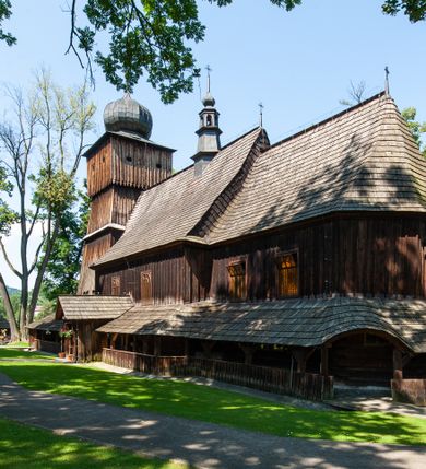 Zdjęcie nr 14: Kościół orientowany, drewniany, na podmurowaniu, o konstrukcji zrębowej, z wieżą o konstrukcji słupowo-ramowej. Składa się z prostokątnej nawy, do której od wschodu przylega węższe prezbiterium zamknięte trójbocznie. Do niego od północy dobudowano prostokątną zakrystię. Do nawy od zachodu przylega wieża na rzucie kwadratu, o ścianach pochyłych, rozdzielona na kondygnacje daszkiem; zwieńczona nadwieszoną izbicą szalowaną pionowymi deskami wyciętymi dołem w ozdobną koronkę; w ścianach izbicy po dwa małe okienka. 
Kościół jednonawowy, z węższym prezbiterium oddzielonym ścianą tęczową. Otwór tęczowy podwójny, górny mniejszy, w strefie sklepień, dolny większy, wycięty w zrębie. Na podniebiu dolnego łuku napis „TEN KOŚCIÓŁ ZAŁOŻONY RP 1789 BENEDYKOWANY RP 1792 MALOWANY RP 1930”. Ściany gładkie, pokryte dekoracją malarską imitującą detale architektoniczne: kolumny, belkowanie, obramienia okien, plafony wypełnione rzeźbiarską dekoracją; między nimi postacie świętych. W nawie od zachodu chór muzyczny wsparty na dwóch, profilowanych słupach, z parapetem wybrzuszonym pośrodku. Nawa i prezbiterium nakryte pozornym sklepieniem kolebkowym z płaskimi odcinkami stropowymi po bokach. 
W nawie głównej cztery okna, w prezbiterium dwa, wszystkie w kształcie stojącego prostokąta; w dolnej kondygnacji wieży dwa okna w kształcie leżącego prostokąta. Wejście główne od zachodu, kolejne od południa, oba portale zamknięte od góry łukiem „w ośli grzbiet”; portal z prezbiterium do zakrystii.  
Kościół obiegają soboty, czyli rodzaj podcieni, zamkniętych wokół wieży, otwartych na pozostałej długości; z kruchtami od zachodu i od południa; cztery kwadratowe okienka w sobotach od zachodu. 
Ściany na zewnątrz kościoła pobite deskami. Nad nawą główną dach dwuspadowy, nad prezbiterium wielopołaciowy, przedłużony od północy na zakrystię. Na dachu nawy zwężająca się ku górze wieżyczka na sygnaturkę, która przechodzi w latarnię o cebulastym zakończeniu. Wieżę zachodnią wieńczy hełm złożony z niskiego dachu namiotowego i nasadzonej na niego bani z kulą i krzyżem. Soboty nakryto dachem pulpitowym, wygiętym przy ścianie wschodniej zakrystii łukowo ku górze po to, aby lepiej ją doświetlić. Dachy kryte gontami, hełmy wież blachą. 
