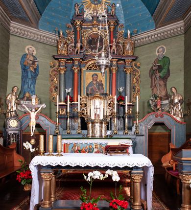 Zdjęcie nr 51: Kościół orientowany, drewniany, na podmurowaniu, o konstrukcji zrębowej, z wieżą o konstrukcji słupowo-ramowej. Składa się z prostokątnej nawy, do której od wschodu przylega węższe prezbiterium zamknięte trójbocznie. Do niego od północy dobudowano prostokątną zakrystię. Do nawy od zachodu przylega wieża na rzucie kwadratu, o ścianach pochyłych, rozdzielona na kondygnacje daszkiem; zwieńczona nadwieszoną izbicą szalowaną pionowymi deskami wyciętymi dołem w ozdobną koronkę; w ścianach izbicy po dwa małe okienka. 
Kościół jednonawowy, z węższym prezbiterium oddzielonym ścianą tęczową. Otwór tęczowy podwójny, górny mniejszy, w strefie sklepień, dolny większy, wycięty w zrębie. Na podniebiu dolnego łuku napis „TEN KOŚCIÓŁ ZAŁOŻONY RP 1789 BENEDYKOWANY RP 1792 MALOWANY RP 1930”. Ściany gładkie, pokryte dekoracją malarską imitującą detale architektoniczne: kolumny, belkowanie, obramienia okien, plafony wypełnione rzeźbiarską dekoracją; między nimi postacie świętych. W nawie od zachodu chór muzyczny wsparty na dwóch, profilowanych słupach, z parapetem wybrzuszonym pośrodku. Nawa i prezbiterium nakryte pozornym sklepieniem kolebkowym z płaskimi odcinkami stropowymi po bokach. 
W nawie głównej cztery okna, w prezbiterium dwa, wszystkie w kształcie stojącego prostokąta; w dolnej kondygnacji wieży dwa okna w kształcie leżącego prostokąta. Wejście główne od zachodu, kolejne od południa, oba portale zamknięte od góry łukiem „w ośli grzbiet”; portal z prezbiterium do zakrystii.  
Kościół obiegają soboty, czyli rodzaj podcieni, zamkniętych wokół wieży, otwartych na pozostałej długości; z kruchtami od zachodu i od południa; cztery kwadratowe okienka w sobotach od zachodu. 
Ściany na zewnątrz kościoła pobite deskami. Nad nawą główną dach dwuspadowy, nad prezbiterium wielopołaciowy, przedłużony od północy na zakrystię. Na dachu nawy zwężająca się ku górze wieżyczka na sygnaturkę, która przechodzi w latarnię o cebulastym zakończeniu. Wieżę zachodnią wieńczy hełm złożony z niskiego dachu namiotowego i nasadzonej na niego bani z kulą i krzyżem. Soboty nakryto dachem pulpitowym, wygiętym przy ścianie wschodniej zakrystii łukowo ku górze po to, aby lepiej ją doświetlić. Dachy kryte gontami, hełmy wież blachą. 
