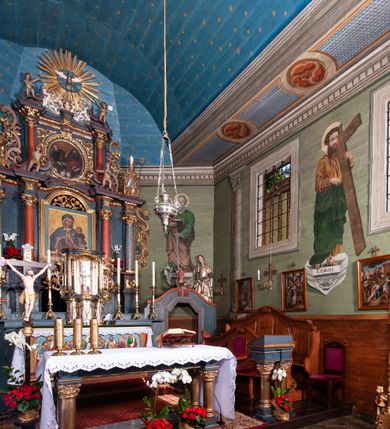 Zdjęcie nr 52: Kościół orientowany, drewniany, na podmurowaniu, o konstrukcji zrębowej, z wieżą o konstrukcji słupowo-ramowej. Składa się z prostokątnej nawy, do której od wschodu przylega węższe prezbiterium zamknięte trójbocznie. Do niego od północy dobudowano prostokątną zakrystię. Do nawy od zachodu przylega wieża na rzucie kwadratu, o ścianach pochyłych, rozdzielona na kondygnacje daszkiem; zwieńczona nadwieszoną izbicą szalowaną pionowymi deskami wyciętymi dołem w ozdobną koronkę; w ścianach izbicy po dwa małe okienka. 
Kościół jednonawowy, z węższym prezbiterium oddzielonym ścianą tęczową. Otwór tęczowy podwójny, górny mniejszy, w strefie sklepień, dolny większy, wycięty w zrębie. Na podniebiu dolnego łuku napis „TEN KOŚCIÓŁ ZAŁOŻONY RP 1789 BENEDYKOWANY RP 1792 MALOWANY RP 1930”. Ściany gładkie, pokryte dekoracją malarską imitującą detale architektoniczne: kolumny, belkowanie, obramienia okien, plafony wypełnione rzeźbiarską dekoracją; między nimi postacie świętych. W nawie od zachodu chór muzyczny wsparty na dwóch, profilowanych słupach, z parapetem wybrzuszonym pośrodku. Nawa i prezbiterium nakryte pozornym sklepieniem kolebkowym z płaskimi odcinkami stropowymi po bokach. 
W nawie głównej cztery okna, w prezbiterium dwa, wszystkie w kształcie stojącego prostokąta; w dolnej kondygnacji wieży dwa okna w kształcie leżącego prostokąta. Wejście główne od zachodu, kolejne od południa, oba portale zamknięte od góry łukiem „w ośli grzbiet”; portal z prezbiterium do zakrystii.  
Kościół obiegają soboty, czyli rodzaj podcieni, zamkniętych wokół wieży, otwartych na pozostałej długości; z kruchtami od zachodu i od południa; cztery kwadratowe okienka w sobotach od zachodu. 
Ściany na zewnątrz kościoła pobite deskami. Nad nawą główną dach dwuspadowy, nad prezbiterium wielopołaciowy, przedłużony od północy na zakrystię. Na dachu nawy zwężająca się ku górze wieżyczka na sygnaturkę, która przechodzi w latarnię o cebulastym zakończeniu. Wieżę zachodnią wieńczy hełm złożony z niskiego dachu namiotowego i nasadzonej na niego bani z kulą i krzyżem. Soboty nakryto dachem pulpitowym, wygiętym przy ścianie wschodniej zakrystii łukowo ku górze po to, aby lepiej ją doświetlić. Dachy kryte gontami, hełmy wież blachą. 
