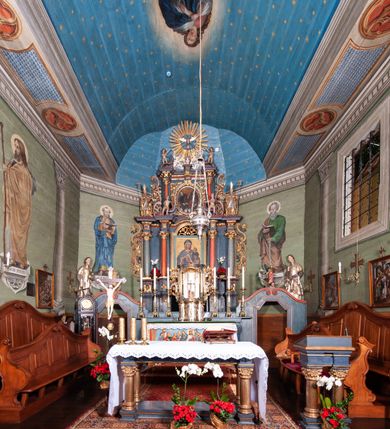 Zdjęcie nr 48: Kościół orientowany, drewniany, na podmurowaniu, o konstrukcji zrębowej, z wieżą o konstrukcji słupowo-ramowej. Składa się z prostokątnej nawy, do której od wschodu przylega węższe prezbiterium zamknięte trójbocznie. Do niego od północy dobudowano prostokątną zakrystię. Do nawy od zachodu przylega wieża na rzucie kwadratu, o ścianach pochyłych, rozdzielona na kondygnacje daszkiem; zwieńczona nadwieszoną izbicą szalowaną pionowymi deskami wyciętymi dołem w ozdobną koronkę; w ścianach izbicy po dwa małe okienka. 
Kościół jednonawowy, z węższym prezbiterium oddzielonym ścianą tęczową. Otwór tęczowy podwójny, górny mniejszy, w strefie sklepień, dolny większy, wycięty w zrębie. Na podniebiu dolnego łuku napis „TEN KOŚCIÓŁ ZAŁOŻONY RP 1789 BENEDYKOWANY RP 1792 MALOWANY RP 1930”. Ściany gładkie, pokryte dekoracją malarską imitującą detale architektoniczne: kolumny, belkowanie, obramienia okien, plafony wypełnione rzeźbiarską dekoracją; między nimi postacie świętych. W nawie od zachodu chór muzyczny wsparty na dwóch, profilowanych słupach, z parapetem wybrzuszonym pośrodku. Nawa i prezbiterium nakryte pozornym sklepieniem kolebkowym z płaskimi odcinkami stropowymi po bokach. 
W nawie głównej cztery okna, w prezbiterium dwa, wszystkie w kształcie stojącego prostokąta; w dolnej kondygnacji wieży dwa okna w kształcie leżącego prostokąta. Wejście główne od zachodu, kolejne od południa, oba portale zamknięte od góry łukiem „w ośli grzbiet”; portal z prezbiterium do zakrystii.  
Kościół obiegają soboty, czyli rodzaj podcieni, zamkniętych wokół wieży, otwartych na pozostałej długości; z kruchtami od zachodu i od południa; cztery kwadratowe okienka w sobotach od zachodu. 
Ściany na zewnątrz kościoła pobite deskami. Nad nawą główną dach dwuspadowy, nad prezbiterium wielopołaciowy, przedłużony od północy na zakrystię. Na dachu nawy zwężająca się ku górze wieżyczka na sygnaturkę, która przechodzi w latarnię o cebulastym zakończeniu. Wieżę zachodnią wieńczy hełm złożony z niskiego dachu namiotowego i nasadzonej na niego bani z kulą i krzyżem. Soboty nakryto dachem pulpitowym, wygiętym przy ścianie wschodniej zakrystii łukowo ku górze po to, aby lepiej ją doświetlić. Dachy kryte gontami, hełmy wież blachą. 
