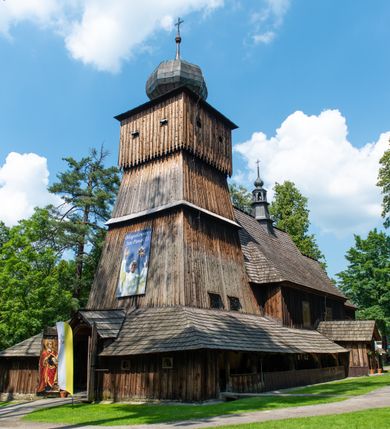 Zdjęcie nr 46: Kościół orientowany, drewniany, na podmurowaniu, o konstrukcji zrębowej, z wieżą o konstrukcji słupowo-ramowej. Składa się z prostokątnej nawy, do której od wschodu przylega węższe prezbiterium zamknięte trójbocznie. Do niego od północy dobudowano prostokątną zakrystię. Do nawy od zachodu przylega wieża na rzucie kwadratu, o ścianach pochyłych, rozdzielona na kondygnacje daszkiem; zwieńczona nadwieszoną izbicą szalowaną pionowymi deskami wyciętymi dołem w ozdobną koronkę; w ścianach izbicy po dwa małe okienka. 
Kościół jednonawowy, z węższym prezbiterium oddzielonym ścianą tęczową. Otwór tęczowy podwójny, górny mniejszy, w strefie sklepień, dolny większy, wycięty w zrębie. Na podniebiu dolnego łuku napis „TEN KOŚCIÓŁ ZAŁOŻONY RP 1789 BENEDYKOWANY RP 1792 MALOWANY RP 1930”. Ściany gładkie, pokryte dekoracją malarską imitującą detale architektoniczne: kolumny, belkowanie, obramienia okien, plafony wypełnione rzeźbiarską dekoracją; między nimi postacie świętych. W nawie od zachodu chór muzyczny wsparty na dwóch, profilowanych słupach, z parapetem wybrzuszonym pośrodku. Nawa i prezbiterium nakryte pozornym sklepieniem kolebkowym z płaskimi odcinkami stropowymi po bokach. 
W nawie głównej cztery okna, w prezbiterium dwa, wszystkie w kształcie stojącego prostokąta; w dolnej kondygnacji wieży dwa okna w kształcie leżącego prostokąta. Wejście główne od zachodu, kolejne od południa, oba portale zamknięte od góry łukiem „w ośli grzbiet”; portal z prezbiterium do zakrystii.  
Kościół obiegają soboty, czyli rodzaj podcieni, zamkniętych wokół wieży, otwartych na pozostałej długości; z kruchtami od zachodu i od południa; cztery kwadratowe okienka w sobotach od zachodu. 
Ściany na zewnątrz kościoła pobite deskami. Nad nawą główną dach dwuspadowy, nad prezbiterium wielopołaciowy, przedłużony od północy na zakrystię. Na dachu nawy zwężająca się ku górze wieżyczka na sygnaturkę, która przechodzi w latarnię o cebulastym zakończeniu. Wieżę zachodnią wieńczy hełm złożony z niskiego dachu namiotowego i nasadzonej na niego bani z kulą i krzyżem. Soboty nakryto dachem pulpitowym, wygiętym przy ścianie wschodniej zakrystii łukowo ku górze po to, aby lepiej ją doświetlić. Dachy kryte gontami, hełmy wież blachą. 
