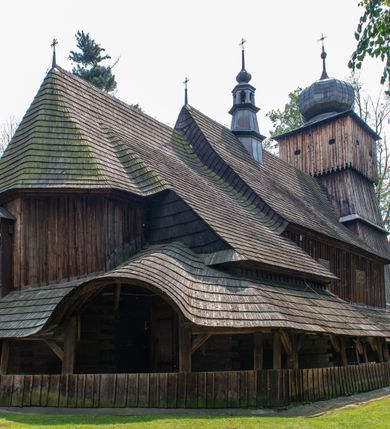 Zdjęcie nr 21: Kościół orientowany, drewniany, na podmurowaniu, o konstrukcji zrębowej, z wieżą o konstrukcji słupowo-ramowej. Składa się z prostokątnej nawy, do której od wschodu przylega węższe prezbiterium zamknięte trójbocznie. Do niego od północy dobudowano prostokątną zakrystię. Do nawy od zachodu przylega wieża na rzucie kwadratu, o ścianach pochyłych, rozdzielona na kondygnacje daszkiem; zwieńczona nadwieszoną izbicą szalowaną pionowymi deskami wyciętymi dołem w ozdobną koronkę; w ścianach izbicy po dwa małe okienka. 
Kościół jednonawowy, z węższym prezbiterium oddzielonym ścianą tęczową. Otwór tęczowy podwójny, górny mniejszy, w strefie sklepień, dolny większy, wycięty w zrębie. Na podniebiu dolnego łuku napis „TEN KOŚCIÓŁ ZAŁOŻONY RP 1789 BENEDYKOWANY RP 1792 MALOWANY RP 1930”. Ściany gładkie, pokryte dekoracją malarską imitującą detale architektoniczne: kolumny, belkowanie, obramienia okien, plafony wypełnione rzeźbiarską dekoracją; między nimi postacie świętych. W nawie od zachodu chór muzyczny wsparty na dwóch, profilowanych słupach, z parapetem wybrzuszonym pośrodku. Nawa i prezbiterium nakryte pozornym sklepieniem kolebkowym z płaskimi odcinkami stropowymi po bokach. 
W nawie głównej cztery okna, w prezbiterium dwa, wszystkie w kształcie stojącego prostokąta; w dolnej kondygnacji wieży dwa okna w kształcie leżącego prostokąta. Wejście główne od zachodu, kolejne od południa, oba portale zamknięte od góry łukiem „w ośli grzbiet”; portal z prezbiterium do zakrystii.  
Kościół obiegają soboty, czyli rodzaj podcieni, zamkniętych wokół wieży, otwartych na pozostałej długości; z kruchtami od zachodu i od południa; cztery kwadratowe okienka w sobotach od zachodu. 
Ściany na zewnątrz kościoła pobite deskami. Nad nawą główną dach dwuspadowy, nad prezbiterium wielopołaciowy, przedłużony od północy na zakrystię. Na dachu nawy zwężająca się ku górze wieżyczka na sygnaturkę, która przechodzi w latarnię o cebulastym zakończeniu. Wieżę zachodnią wieńczy hełm złożony z niskiego dachu namiotowego i nasadzonej na niego bani z kulą i krzyżem. Soboty nakryto dachem pulpitowym, wygiętym przy ścianie wschodniej zakrystii łukowo ku górze po to, aby lepiej ją doświetlić. Dachy kryte gontami, hełmy wież blachą. 
