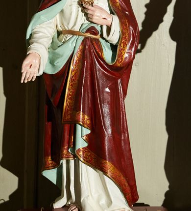 Zdjęcie nr 1: Rzeźba pełnoplastyczna na prostopadłościennej podstawie z otworami na drążki, przedstawiająca Chrystusa stojącego frontalnie w kontrapoście. Prawą ręką dotyka unoszącego się przed jego piersią gorejącego serca ujętego koroną cierniową i zwieńczonego krzyżem. Lewą rękę wyciąga przed siebie prezentując ranę. Głowa lekko przechylona, wzrok skierowany przed siebie, oczy jasne, nos prosty, usta niewielkie, czerwone. Na twarzy krótki brązowy zarost, falowane włosy opadają na ramiona i plecy. Chrystus jest ubrany w białą suknię z długimi rękawami, przewiązaną w pasie złotym sznurem, za który ma zatknięty czerwony płaszcz z jasnozielonym podszyciem i pasem złotego ornamentu przy brzegu okrywający ramiona i nogi. Polichromia w partiach ciała naturalistyczna. Rzeźba stoi na bordowym cokole umocowanym na ciemnobrązowej podstawie. 
