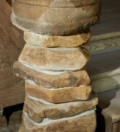 Zdjęcie nr 1: Kropielnica wolnostojąca składająca się z czary ustawionej na ośmiu płaskich kamieniach złączonych ze sobą zaprawą. Czara ma zarys koła, dekorowana jest dwoma półwałkami –  jednym u podstawy, a drugim poniżej wylewu. Kolor naturalny. 
