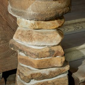 Zdjęcie nr 1: Kropielnica wolnostojąca składająca się z czary ustawionej na ośmiu płaskich kamieniach złączonych ze sobą zaprawą. Czara ma zarys koła, dekorowana jest dwoma półwałkami –  jednym u podstawy, a drugim poniżej wylewu. Kolor naturalny. 
