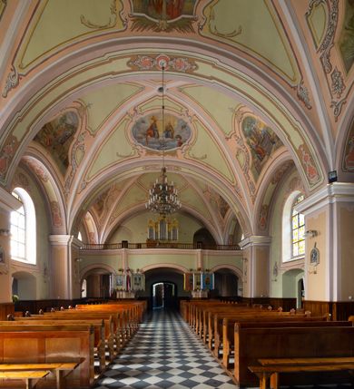 Zdjęcie nr 16: Kościół murowany, jednonawowy, na rzucie prostokąta, z późniejszymi dobudówkami. Prezbiterium usytuowane od północy, jednoprzęsłowe, węższe od korpusu, zamknięte półkolistą absydą. Do prezbiterium dobudowana zakrystia od wschodu oraz kaplica od zachodu poprzedzona niewielką kruchtą. Nawa główna trójprzęsłowa z partią wieżową niewyróżniającą się w bryle. Po bokach przęsła środkowego dostawione dwie kaplice na rzucie kwadratu: od wschodu Matki Boskiej Częstochowskiej, od zachodu św. Maksymiliana Marii Kolbego. Chór muzyczny wsparty na trzech arkadach. W prezbiterium sklepienie żaglaste, a w nawie krzyżowe, pozorne, oddzielone gurtami wychodzącymi z potężnych filarów przyściennych. Okna prostokątne, zamknięte półkoliście znajdują się w nawie, kaplicy przy prezbiterium, w wieży i w ścianach bocznych absydy. Natomiast w ścianach bocznych prezbiterium, na osi absydy i w kaplicach przy nawie okna koliste. Okna w większości wypełnione witrażami ze scenami figuralnymi, w innych ozdobne przeszklenia geometryczne. Fasada trójosiowa, na osi środkowej usytuowana wieża, delikatnie wystająca przed lico fasady, o podziałach ramowych, nakryta baniastym hełmem z dwukondygnacyjną latarnią. Osie boczne zwieńczone spływami wolutowymi. Dachy gontowe.

