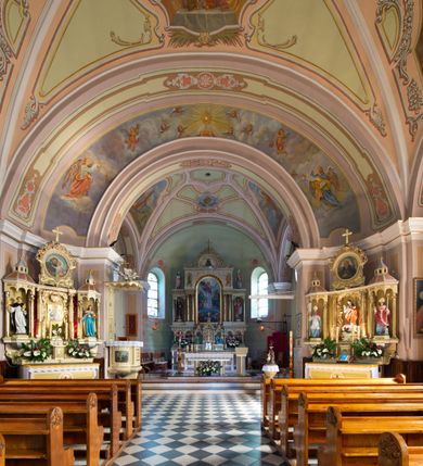 Zdjęcie nr 11: Kościół murowany, jednonawowy, na rzucie prostokąta, z późniejszymi dobudówkami. Prezbiterium usytuowane od północy, jednoprzęsłowe, węższe od korpusu, zamknięte półkolistą absydą. Do prezbiterium dobudowana zakrystia od wschodu oraz kaplica od zachodu poprzedzona niewielką kruchtą. Nawa główna trójprzęsłowa z partią wieżową niewyróżniającą się w bryle. Po bokach przęsła środkowego dostawione dwie kaplice na rzucie kwadratu: od wschodu Matki Boskiej Częstochowskiej, od zachodu św. Maksymiliana Marii Kolbego. Chór muzyczny wsparty na trzech arkadach. W prezbiterium sklepienie żaglaste, a w nawie krzyżowe, pozorne, oddzielone gurtami wychodzącymi z potężnych filarów przyściennych. Okna prostokątne, zamknięte półkoliście znajdują się w nawie, kaplicy przy prezbiterium, w wieży i w ścianach bocznych absydy. Natomiast w ścianach bocznych prezbiterium, na osi absydy i w kaplicach przy nawie okna koliste. Okna w większości wypełnione witrażami ze scenami figuralnymi, w innych ozdobne przeszklenia geometryczne. Fasada trójosiowa, na osi środkowej usytuowana wieża, delikatnie wystająca przed lico fasady, o podziałach ramowych, nakryta baniastym hełmem z dwukondygnacyjną latarnią. Osie boczne zwieńczone spływami wolutowymi. Dachy gontowe.

