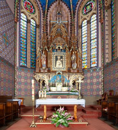 Zdjęcie nr 4: Kościół jest położony na północny-zachód od centrum miejscowości, na placu otoczonym ceglanym murem na podmurówce z murowanymi słupkami, nakrytym blaszanym daszkiem. Główne wejście na plac kościelny prowadzi przez pseudobastionową bramę, flankowaną dwiema pseudowieżyczkami oraz dwiema furtkami. Kościół jest budowlą założoną na planie krzyża łacińskiego, murowaną z cegły, orientowaną, jednonawową z transeptem, prezbiterium zakończonym trójbocznie i wieżą. Od północnej strony kościoła prostokątna zakrystia, od południa w narożniku korpusu i prezbiterium niewielkie kruchty. 

Wnętrze artykułowe ostrołukowymi arkadami wspartymi na filarach. Korpus sześcioprzęsłowy, nakryty sklepieniem krzyżowo-żebrowym; prezbiterium dwuprzęsłowe, węższe od korpusu ze sklepieniem gwiaździstym. Chór muzyczny wsparty na trzech arkadach. W kościele duże okna pseudomaswerkowe w kształcie stojących prostokątów, zamkniętych ostrołukowo, wypełnione witrażami.

Na zewnątrz elewacje ceglane z kamiennym cokołem, zamknięte kamiennym gzymsem podokapowym. Od fasady po lewej stronie dostawiona masywna wieża na planie kwadratu, czwórkondygnacyjna. W dolnych kondygnacjach niewielkie okienka, trzecia kondygnacja najwyższa, a w niej wysokie prześwity okienne z biforiami, wyżej zegary na każdej ścianie wieży. Ostatnia kondygnacja najwyższa z otworami okiennymi w kształcie leżących prostokątów, zamkniętych odcinkowo, wypełnionych podwójnymi biforiami. Wieża nakryta ostrosłupowym hełmem z analogicznymi czterema mniejszymi hełmami w narożach. Po prawej stronie fasady kruchta wejściowa do kościoła założona na planie prostokąta z portalem od zachodu, nakryta daszkiem jednospadowym, od południa zwieńczonym kamiennym szczytem schodkowym. Portal wysunięty przed lico kruchty, w polu ostrołukowa arkada z tympanonem przedstawiającym Chrystusa spotykającego Marię Magdalenę. Portal zamknięty trójkątnym szczytem, którego pole wypełnione jest rzeźbioną dekoracją z liści i owoców winnego grona oraz krzyża łacińskiego pośrodku. Za kruchtą ściana zachodnia kościoła zamknięta trójkątnym szczytem schodkowym, wypełnionym blendami. Analogiczne szczyty na zakończeniu ramion transeptu oraz na zakończeniu korpusu nawy kościoła od strony wschodniej. Nad skrzyżowaniem ramion transeptu umieszczona jest wieżyczka na sygnaturkę. Do świątyni prowadzą też dwa mniejsze wejścia od strony południowej przez kruchty oraz trzecie przez zakrystię. Korpus nakryty wysokim, dwuspadowym dachem. Ramiona transeptu nakryte osobnymi dachami dwuspadowymi o kalenicy niższej niż dach korpusu. Na zewnątrz kościół oszkarpowany. 