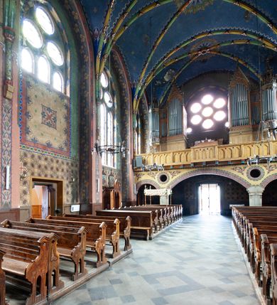 Zdjęcie nr 8: Kościół jest położony na północny-zachód od centrum miejscowości, na placu otoczonym ceglanym murem na podmurówce z murowanymi słupkami, nakrytym blaszanym daszkiem. Główne wejście na plac kościelny prowadzi przez pseudobastionową bramę, flankowaną dwiema pseudowieżyczkami oraz dwiema furtkami. Kościół jest budowlą założoną na planie krzyża łacińskiego, murowaną z cegły, orientowaną, jednonawową z transeptem, prezbiterium zakończonym trójbocznie i wieżą. Od północnej strony kościoła prostokątna zakrystia, od południa w narożniku korpusu i prezbiterium niewielkie kruchty. 

Wnętrze artykułowe ostrołukowymi arkadami wspartymi na filarach. Korpus sześcioprzęsłowy, nakryty sklepieniem krzyżowo-żebrowym; prezbiterium dwuprzęsłowe, węższe od korpusu ze sklepieniem gwiaździstym. Chór muzyczny wsparty na trzech arkadach. W kościele duże okna pseudomaswerkowe w kształcie stojących prostokątów, zamkniętych ostrołukowo, wypełnione witrażami.

Na zewnątrz elewacje ceglane z kamiennym cokołem, zamknięte kamiennym gzymsem podokapowym. Od fasady po lewej stronie dostawiona masywna wieża na planie kwadratu, czwórkondygnacyjna. W dolnych kondygnacjach niewielkie okienka, trzecia kondygnacja najwyższa, a w niej wysokie prześwity okienne z biforiami, wyżej zegary na każdej ścianie wieży. Ostatnia kondygnacja najwyższa z otworami okiennymi w kształcie leżących prostokątów, zamkniętych odcinkowo, wypełnionych podwójnymi biforiami. Wieża nakryta ostrosłupowym hełmem z analogicznymi czterema mniejszymi hełmami w narożach. Po prawej stronie fasady kruchta wejściowa do kościoła założona na planie prostokąta z portalem od zachodu, nakryta daszkiem jednospadowym, od południa zwieńczonym kamiennym szczytem schodkowym. Portal wysunięty przed lico kruchty, w polu ostrołukowa arkada z tympanonem przedstawiającym Chrystusa spotykającego Marię Magdalenę. Portal zamknięty trójkątnym szczytem, którego pole wypełnione jest rzeźbioną dekoracją z liści i owoców winnego grona oraz krzyża łacińskiego pośrodku. Za kruchtą ściana zachodnia kościoła zamknięta trójkątnym szczytem schodkowym, wypełnionym blendami. Analogiczne szczyty na zakończeniu ramion transeptu oraz na zakończeniu korpusu nawy kościoła od strony wschodniej. Nad skrzyżowaniem ramion transeptu umieszczona jest wieżyczka na sygnaturkę. Do świątyni prowadzą też dwa mniejsze wejścia od strony południowej przez kruchty oraz trzecie przez zakrystię. Korpus nakryty wysokim, dwuspadowym dachem. Ramiona transeptu nakryte osobnymi dachami dwuspadowymi o kalenicy niższej niż dach korpusu. Na zewnątrz kościół oszkarpowany. 