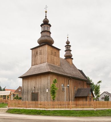 Zdjęcie nr 1: Kościół zlokalizowany na zachodnim krańcu wsi. Plac kościelny otoczony drewnianym płotem. W północno-wschodnim narożu drewniana dzwonnica.  
Kościół orientowany, drewniany, konstrukcji zrębowej, z wieżą na słup od zachodu, wejście główne od zachodu; wejścia boczne od południa przez kruchtę i od północy przez zakrystię. Prezbiterium zamknięte wielobocznie, nawa na rzucie prostokąta. Przy prezbiterium i nawie od północy zakrystia z przedsionkiem, przy nawie od południa kruchta. Wewnątrz stropy, podkreślone profilowanym gzymsem. Łuk tęczowy o wykroju prostokątnym ze ściętymi narożami, flankowany filarkami z belkowaniem; na nim późnobarokowy krucyfiks podtrzymywany przez aniołka, ponad belkowaniem aniołki dzierżące narzędzia Męki Pańskiej. Drugi łuk tęczowy usytuowany na granicy przedłużenia naw o podobnym wykroju. Chór muzyczny wsparty na dwóch żłobkowanych słupach o falistym przebiegu. Ściany nawy przeprute: od północy oknem o kształcie prostokąta, od południa trzema analogicznymi oknami i zwieńczone profilowanym gzymsem. Obramienia okienne fazowane, z nadokiennikami o wykroju w ośli grzbiet. Drzwi prowadzące do kruchty w kształcie prostokąta. Prezbiterium wzniesione o jeden stopień powyżej poziomu nawy, od południa przeprute dwoma prostokątnymi oknami. Od północy drzwi do zakrystii o kształcie stojącego prostokąta, od strony zakrystii profilowane. Zakrystia na planie prostokąta, przylegająca od północy do prezbiterium kościoła. Nawa i kruchta kryte dachem dwuspadowym, prezbiterium trójpołaciowym, opadającym ku wschodowi, zakrystia dachem pulpitowym. Przy wschodnim krańcu dachu nawy znajduje się wieżyczka na sygnaturkę. Dzwonnica drewniana, dwukondygnacyjna na planie zbliżonym do kwadratu. Nad pierwszą kondygnacją dach okapowy, a nad drugą czterospadowy, zwieńczony kulą z krzyżem. Na fasadzie kruchty wnęka z rzeźbą Matki Boskiej z Dzieciątkiem. 



