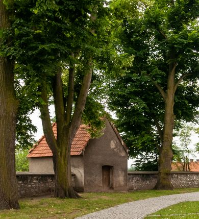 Zdjęcie nr 14: Kościół orientowany, murowany, jednonawowy z prezbiterium zakończonym wielobocznie. Wschodnia część węższa, prostokątna, zachodnia szersza, trójnawowa, halowa. Do prezbiterium od północy przylega zakrystia, do wschodniej części korpusu przybudówka, od zachodu kruchta. Ściany nawy dzielą pilastry. Prezbiterium sklepione krzyżowo, absyda konchowo z lunetami, nawy kolebkowo z lunetami. Od zachodu chór wsparty na dwóch czworobocznych słupach. Jego parapet jest wybrzuszony w części środkowej, ażurowy, zakończony u dołu listwą wycinaną w formie stylizowanych listków. W prezbiterium jedno okno w kształcie stojącego prostokąta zamknięte łukiem pełnym i jedno ślepe, zamknięte łukiem ostrym. Od strony  północnej do zakrystii dwa okna zamknięte łukiem odcinkowym i cztery prostokątne, dwa okna zamknięte łukiem pełnym do zachodniej części nawy; od strony południowej pięć okien zamkniętych łukiem pełnym. Główne wejście od zachodu, drugie od południa, kolejne do  zakrystii, portal z prezbiterium do zakrystii, z czarnego marmuru. Fasada dwuwieżowa, z kruchtą, do której prowadzi ciąg schodów. Kruchta prostopadłościenna, z dachem dwuspadowym, z portalem w kształcie prostokąta zamkniętego łukiem pełnym na osi między oknami powtarzającymi ten kształt. Nad kondygnacją trójkątny przyczółek z krzyżem łacińskim. Fasada dwukondygnacyjna, z wieżami wtopionymi w lico. Pierwsza kondygnacja gładka, flankowana szkarpami, zamknięta gzymsem, druga również niemal gładka, z zegarem na środku i małymi oknami w partii wież. Na osi trójkątny przyczółek. Elewacje obiega cokół, wspierają szkarpy – najgęściej ustawione wokół prezbiterium. Dachy naw dwuspadowe, nad prezbiterium dach zakończony wielobocznie, nad zakrystią pulpitowy; na kalenicy wieżyczka na sygnaturkę, wieże zakończone rozbudowanymi hełmami. 
We wnętrzu na uwagę zasługują chrzcielnica z czarnego marmuru z XVII wieku, obraz św. Izydora w prawym, bocznym ołtarzu według tradycji pędzla Michała Stachowicza i późnobarokowe ołtarze. Prowadzący do zakrystii portal z czarnego marmuru i ołtarz boczny lewy Ukrzyżowania pochodzą, według niektórych przekazów, z krakowskiego kościoła Wszystkich Świętych. 
