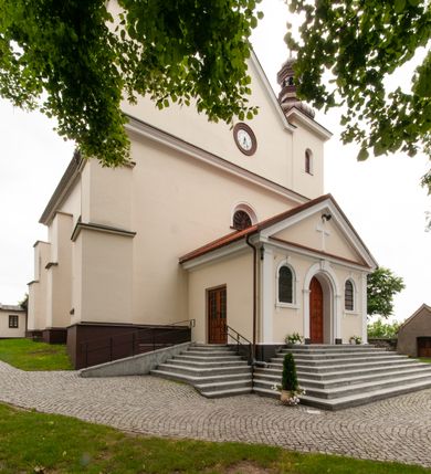 Zdjęcie nr 12: Kościół orientowany, murowany, jednonawowy z prezbiterium zakończonym wielobocznie. Wschodnia część węższa, prostokątna, zachodnia szersza, trójnawowa, halowa. Do prezbiterium od północy przylega zakrystia, do wschodniej części korpusu przybudówka, od zachodu kruchta. Ściany nawy dzielą pilastry. Prezbiterium sklepione krzyżowo, absyda konchowo z lunetami, nawy kolebkowo z lunetami. Od zachodu chór wsparty na dwóch czworobocznych słupach. Jego parapet jest wybrzuszony w części środkowej, ażurowy, zakończony u dołu listwą wycinaną w formie stylizowanych listków. W prezbiterium jedno okno w kształcie stojącego prostokąta zamknięte łukiem pełnym i jedno ślepe, zamknięte łukiem ostrym. Od strony  północnej do zakrystii dwa okna zamknięte łukiem odcinkowym i cztery prostokątne, dwa okna zamknięte łukiem pełnym do zachodniej części nawy; od strony południowej pięć okien zamkniętych łukiem pełnym. Główne wejście od zachodu, drugie od południa, kolejne do  zakrystii, portal z prezbiterium do zakrystii, z czarnego marmuru. Fasada dwuwieżowa, z kruchtą, do której prowadzi ciąg schodów. Kruchta prostopadłościenna, z dachem dwuspadowym, z portalem w kształcie prostokąta zamkniętego łukiem pełnym na osi między oknami powtarzającymi ten kształt. Nad kondygnacją trójkątny przyczółek z krzyżem łacińskim. Fasada dwukondygnacyjna, z wieżami wtopionymi w lico. Pierwsza kondygnacja gładka, flankowana szkarpami, zamknięta gzymsem, druga również niemal gładka, z zegarem na środku i małymi oknami w partii wież. Na osi trójkątny przyczółek. Elewacje obiega cokół, wspierają szkarpy – najgęściej ustawione wokół prezbiterium. Dachy naw dwuspadowe, nad prezbiterium dach zakończony wielobocznie, nad zakrystią pulpitowy; na kalenicy wieżyczka na sygnaturkę, wieże zakończone rozbudowanymi hełmami. 
We wnętrzu na uwagę zasługują chrzcielnica z czarnego marmuru z XVII wieku, obraz św. Izydora w prawym, bocznym ołtarzu według tradycji pędzla Michała Stachowicza i późnobarokowe ołtarze. Prowadzący do zakrystii portal z czarnego marmuru i ołtarz boczny lewy Ukrzyżowania pochodzą, według niektórych przekazów, z krakowskiego kościoła Wszystkich Świętych. 
