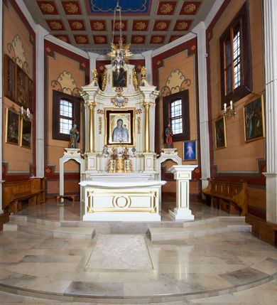 Zdjęcie nr 26: Kościół usytuowany jest w centrum wsi na niewielkim wzniesieniu, orientowany, drewniany, o konstrukcji zrębowej, oszalowany. Jego bryłę tworzy trójbocznie zamknięte prezbiterium, jednonawowy korpus, zakrystia skomunikowana ze skarbcem oraz kruchty od południa i zachodu. Całość pokrywają oddzielne dla nawy i prezbiterium dachy, nad nawą znajduje się wieżyczka na sygnaturkę. Wnętrza niższego, trójbocznie zamkniętego prezbiterium i szerszej, prawie kwadratowej nawy nakryte są stropem. Ściany kościoła zostały podzielone na przęsła kanelowanymi pilastrami ustawionymi na cokołach i zwieńczone profilowanym gzymsem, wyłamującym się na kapitelach. W prezbiterium znajdują się dwa okna od południa i dwa w bocznych ścianach wschodniego zamknięcia; korpus jest oświetlony od południa dwoma oknami. Wszystkie okna zamknięte są łukiem odcinkowym i umieszczone w prostokątnych obramieniach. Przestrzeń między prezbiterium a nawą jest nieznacznie zawężona wydatnymi pilastrami ustawionymi pod arkadą tęczową o łuku koszowym. W środkowym przęśle prezbiterium znajduje się wejście do północnej zakrystii, z profilowanym portalem zamkniętym łukiem trójlistnie ściętym. Na osi ściany południowej umieszczono prostokątny portal, ozdobiony od strony kruchty profilowaniem, a w nadprożu zdwojonym łukiem w  „ośli grzbiet”. Pod nim ornament arkadkowy i wyryta data „1547”. Główne wejście w ścianie zachodniej obejmuje profilowany od strony kruchty portal, który podobnie jak poprzedni zamknięty jest zdwojonym łukiem w „ośli grzbiet”. Chór muzyczny opiera się na dwóch kwadratowych słupach ustawionych diagonalnie (górą dekoracyjnie wycinanych), z parapetem o linii wklęsło-wypukłej. W południowo-zachodnim narożu znajdują się schody na chór osłonięte deskami. Zakrystia jest założona na rzucie prostokąta, przekryta pułapem, z lisicami na ścianie południowej i zachodniej. W osi ściany wschodniej zakrystii umieszczono okno zamknięte łukiem odcinkowym, a w narożu południowo-zachodnim schody na ambonę. W zachodniej ścianie zakrystii znajduje się prostokątne przejście do wąskiego przedsionka i dalej do dawnego skarbca przylegającego do korpusu. Kruchty są założone na rzucie prostokąta, wzdłużnie przylegającego do korpusu i przykryte stropem. Naprzeciw fasady ustawiono wolnostojącą, murowaną dzwonnicę.