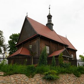 Zdjęcie nr 1: Kościół usytuowany jest w centrum wsi na niewielkim wzniesieniu, orientowany, drewniany, o konstrukcji zrębowej, oszalowany. Jego bryłę tworzy trójbocznie zamknięte prezbiterium, jednonawowy korpus, zakrystia skomunikowana ze skarbcem oraz kruchty od południa i zachodu. Całość pokrywają oddzielne dla nawy i prezbiterium dachy, nad nawą znajduje się wieżyczka na sygnaturkę. Wnętrza niższego, trójbocznie zamkniętego prezbiterium i szerszej, prawie kwadratowej nawy nakryte są stropem. Ściany kościoła zostały podzielone na przęsła kanelowanymi pilastrami ustawionymi na cokołach i zwieńczone profilowanym gzymsem, wyłamującym się na kapitelach. W prezbiterium znajdują się dwa okna od południa i dwa w bocznych ścianach wschodniego zamknięcia; korpus jest oświetlony od południa dwoma oknami. Wszystkie okna zamknięte są łukiem odcinkowym i umieszczone w prostokątnych obramieniach. Przestrzeń między prezbiterium a nawą jest nieznacznie zawężona wydatnymi pilastrami ustawionymi pod arkadą tęczową o łuku koszowym. W środkowym przęśle prezbiterium znajduje się wejście do północnej zakrystii, z profilowanym portalem zamkniętym łukiem trójlistnie ściętym. Na osi ściany południowej umieszczono prostokątny portal, ozdobiony od strony kruchty profilowaniem, a w nadprożu zdwojonym łukiem w  „ośli grzbiet”. Pod nim ornament arkadkowy i wyryta data „1547”. Główne wejście w ścianie zachodniej obejmuje profilowany od strony kruchty portal, który podobnie jak poprzedni zamknięty jest zdwojonym łukiem w „ośli grzbiet”. Chór muzyczny opiera się na dwóch kwadratowych słupach ustawionych diagonalnie (górą dekoracyjnie wycinanych), z parapetem o linii wklęsło-wypukłej. W południowo-zachodnim narożu znajdują się schody na chór osłonięte deskami. Zakrystia jest założona na rzucie prostokąta, przekryta pułapem, z lisicami na ścianie południowej i zachodniej. W osi ściany wschodniej zakrystii umieszczono okno zamknięte łukiem odcinkowym, a w narożu południowo-zachodnim schody na ambonę. W zachodniej ścianie zakrystii znajduje się prostokątne przejście do wąskiego przedsionka i dalej do dawnego skarbca przylegającego do korpusu. Kruchty są założone na rzucie prostokąta, wzdłużnie przylegającego do korpusu i przykryte stropem. Naprzeciw fasady ustawiono wolnostojącą, murowaną dzwonnicę.